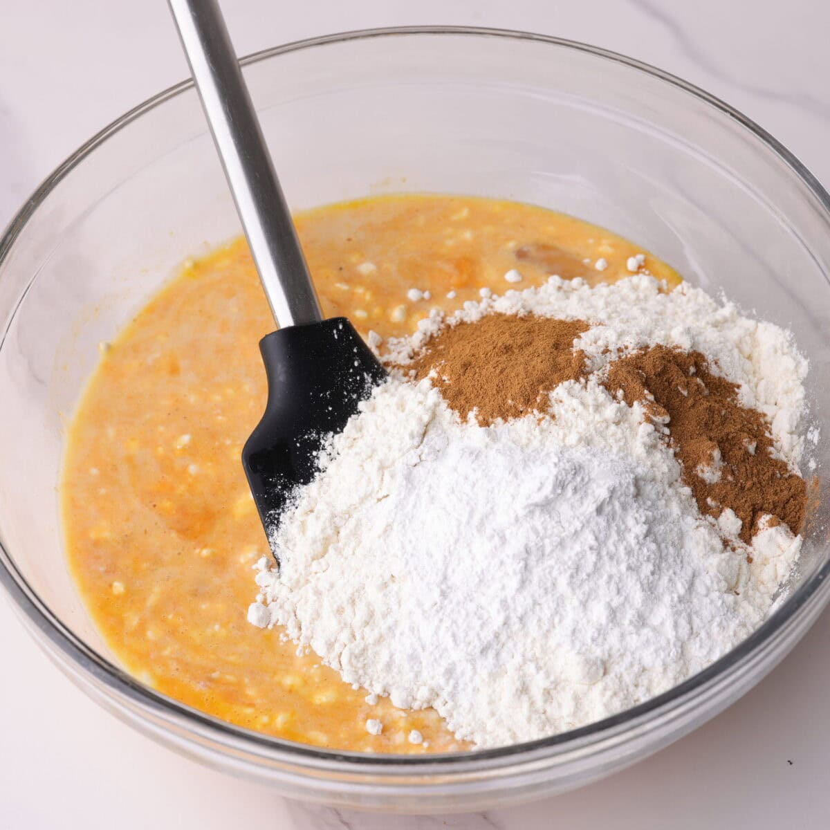 Liquid ingredients with dry ingredients on top in a mixing bowl.