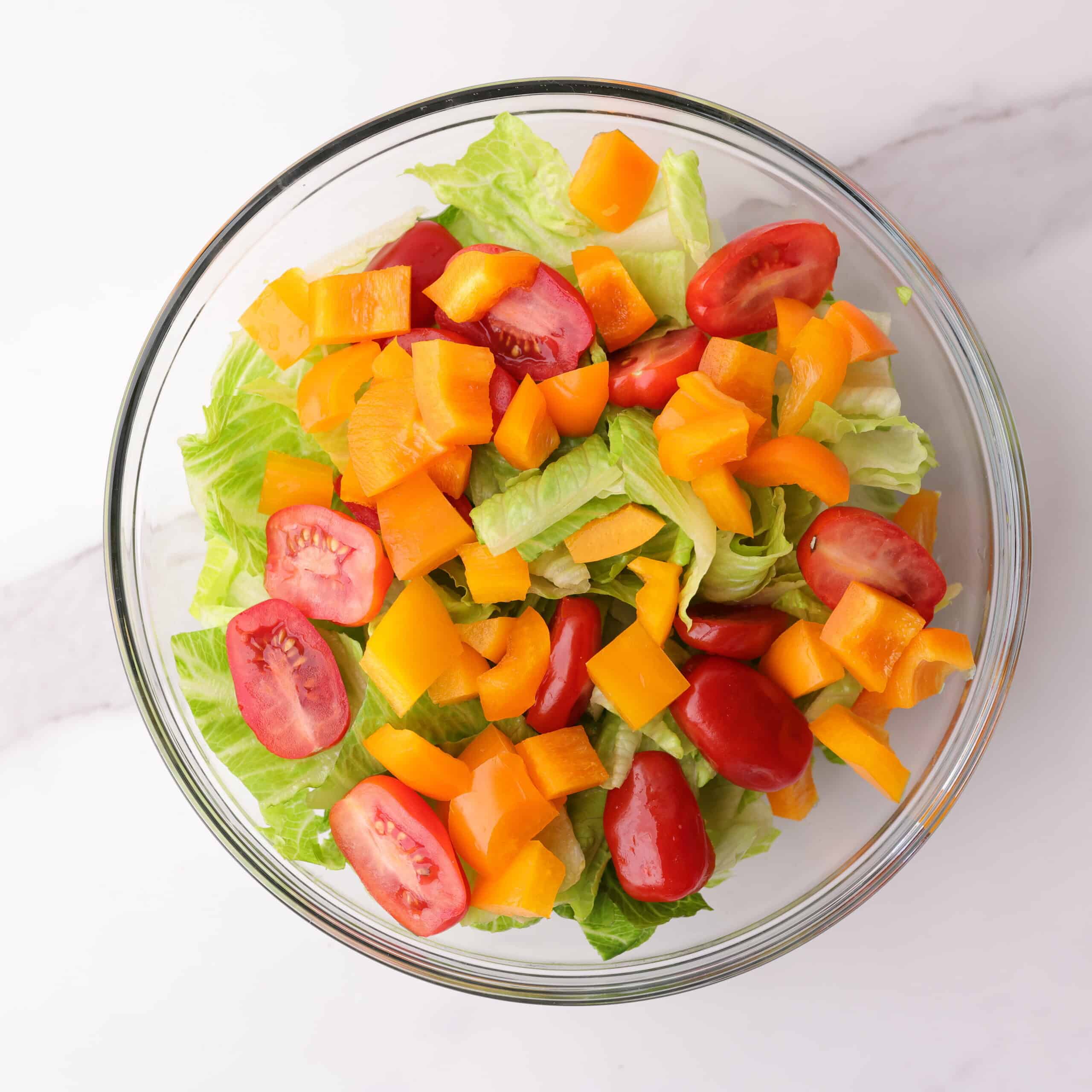 A bowl of the salad prepped with veggies but without dressing or chicken.