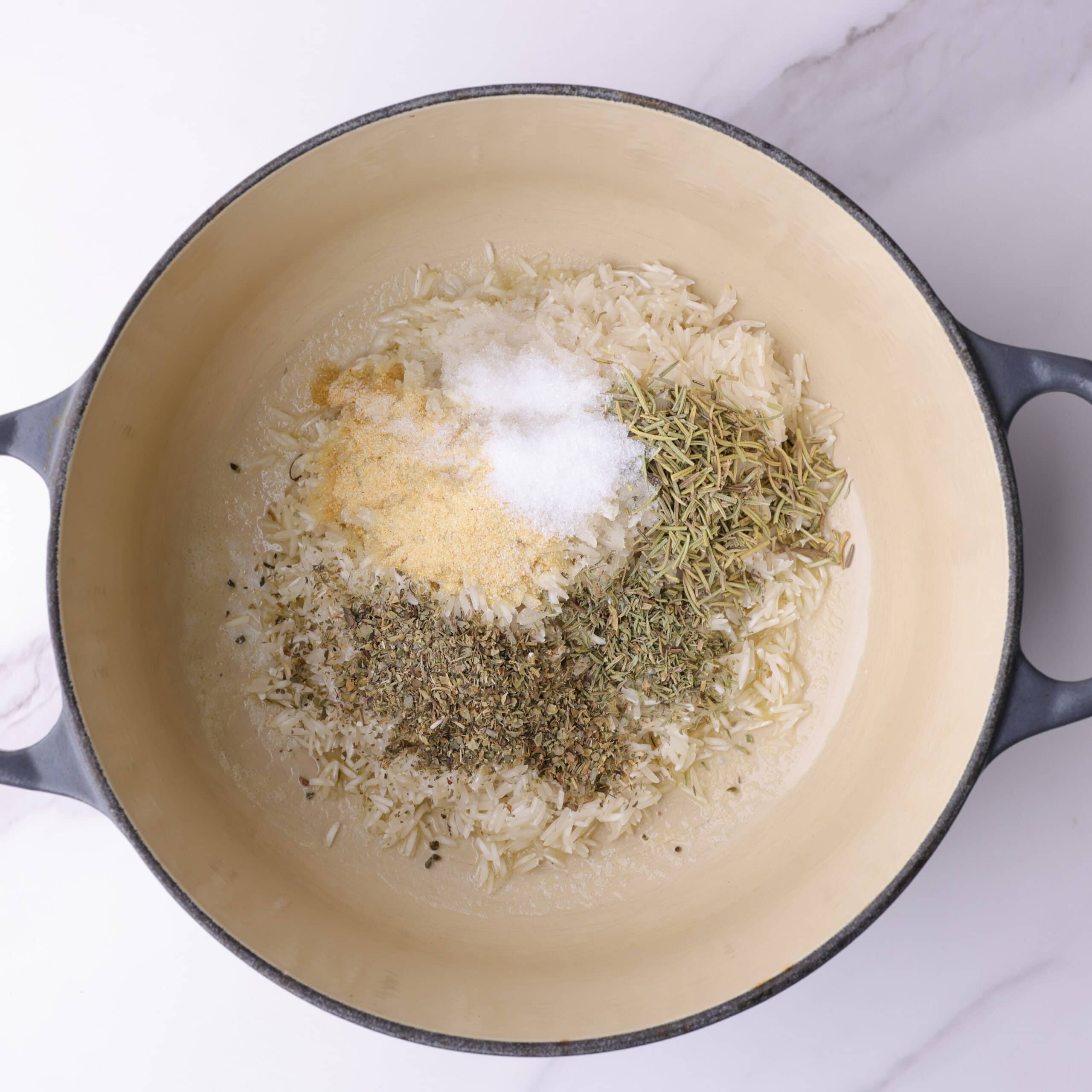 The basmati rice in the medium pot, sprinkled with the rosemary, thyme, Italian seasoning, garlic powder and salt.