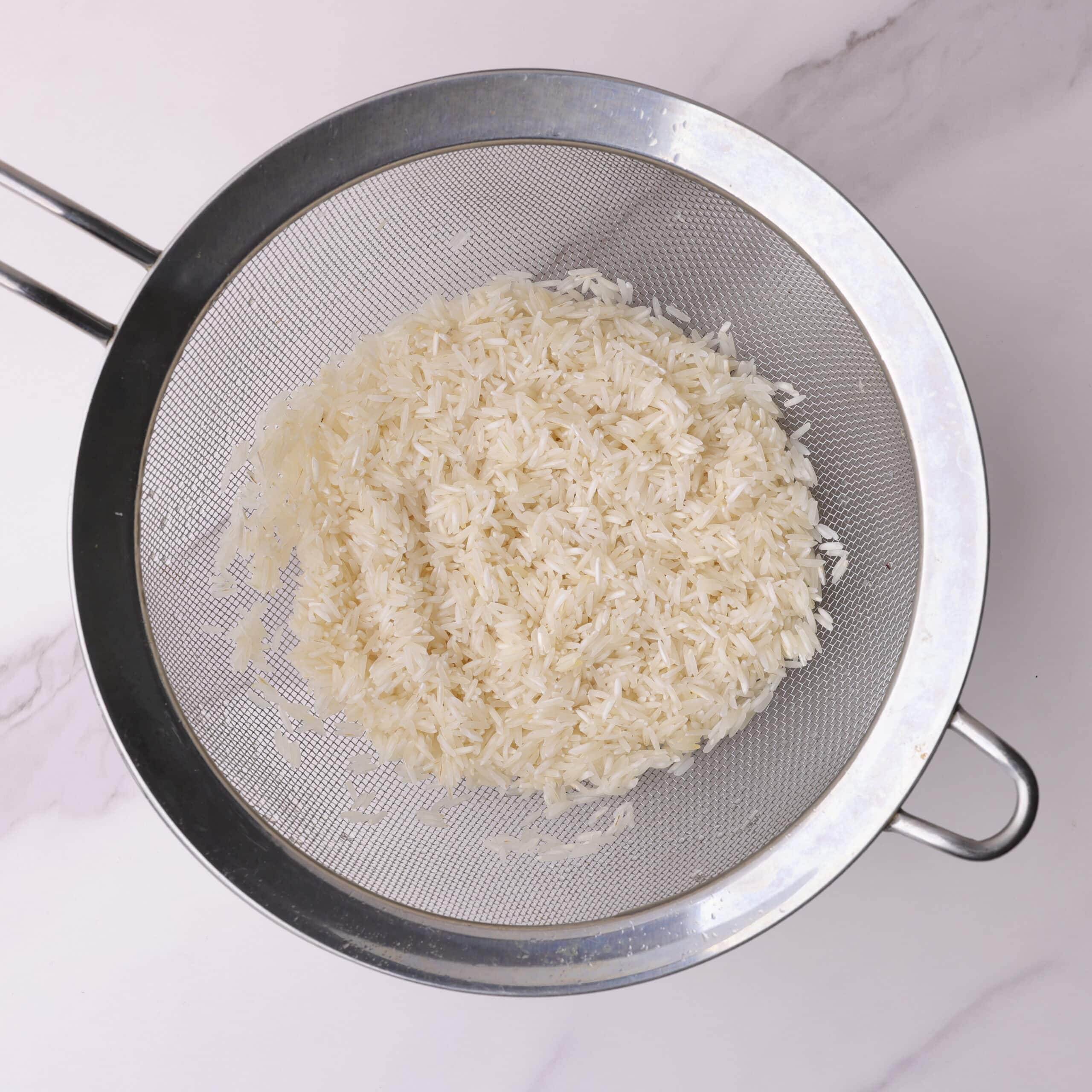 Basmati Rice in a strainer that has been rinsed until the water runs clear.