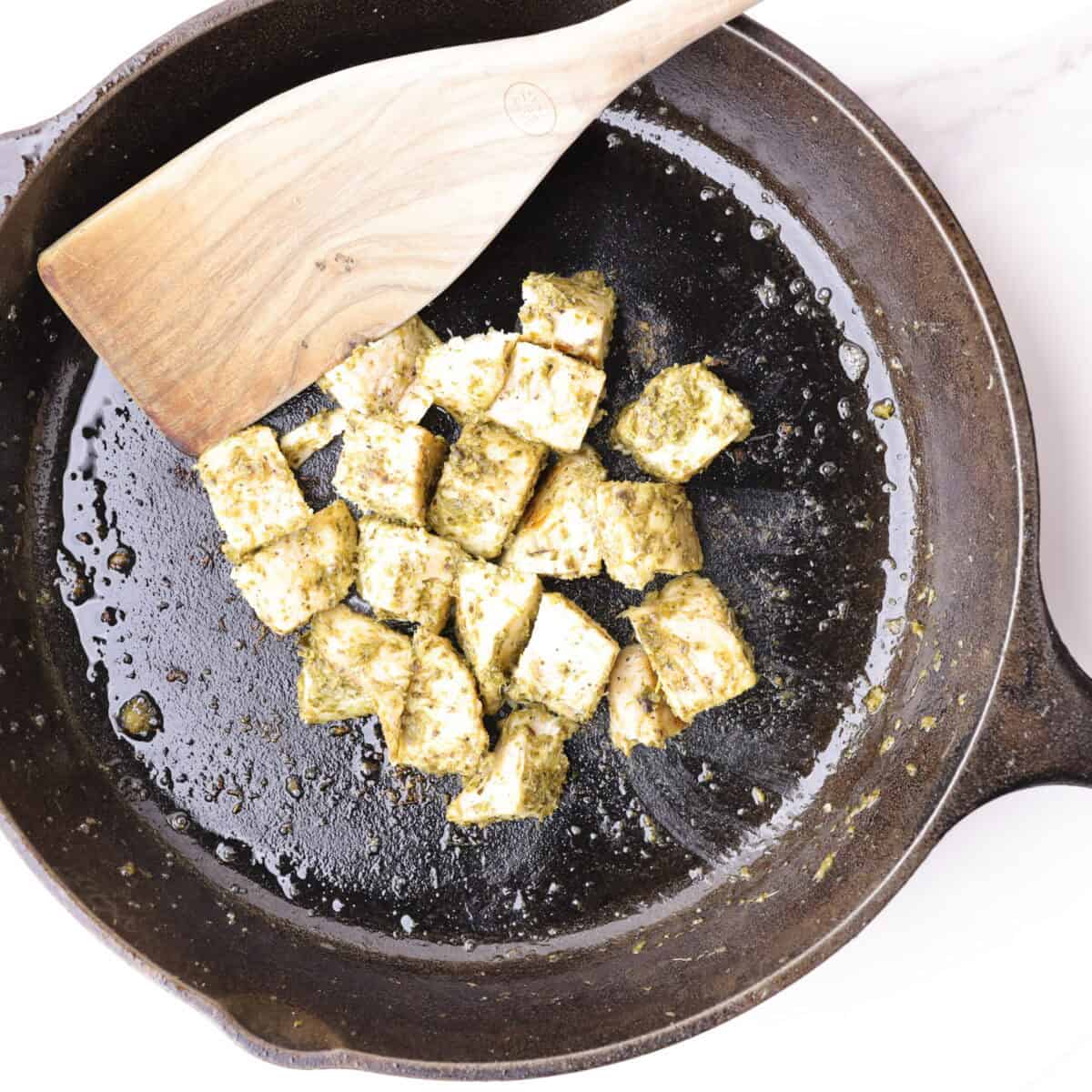 Chicken and pesto heated in the skillet until the chicken is well coated in the pesto.