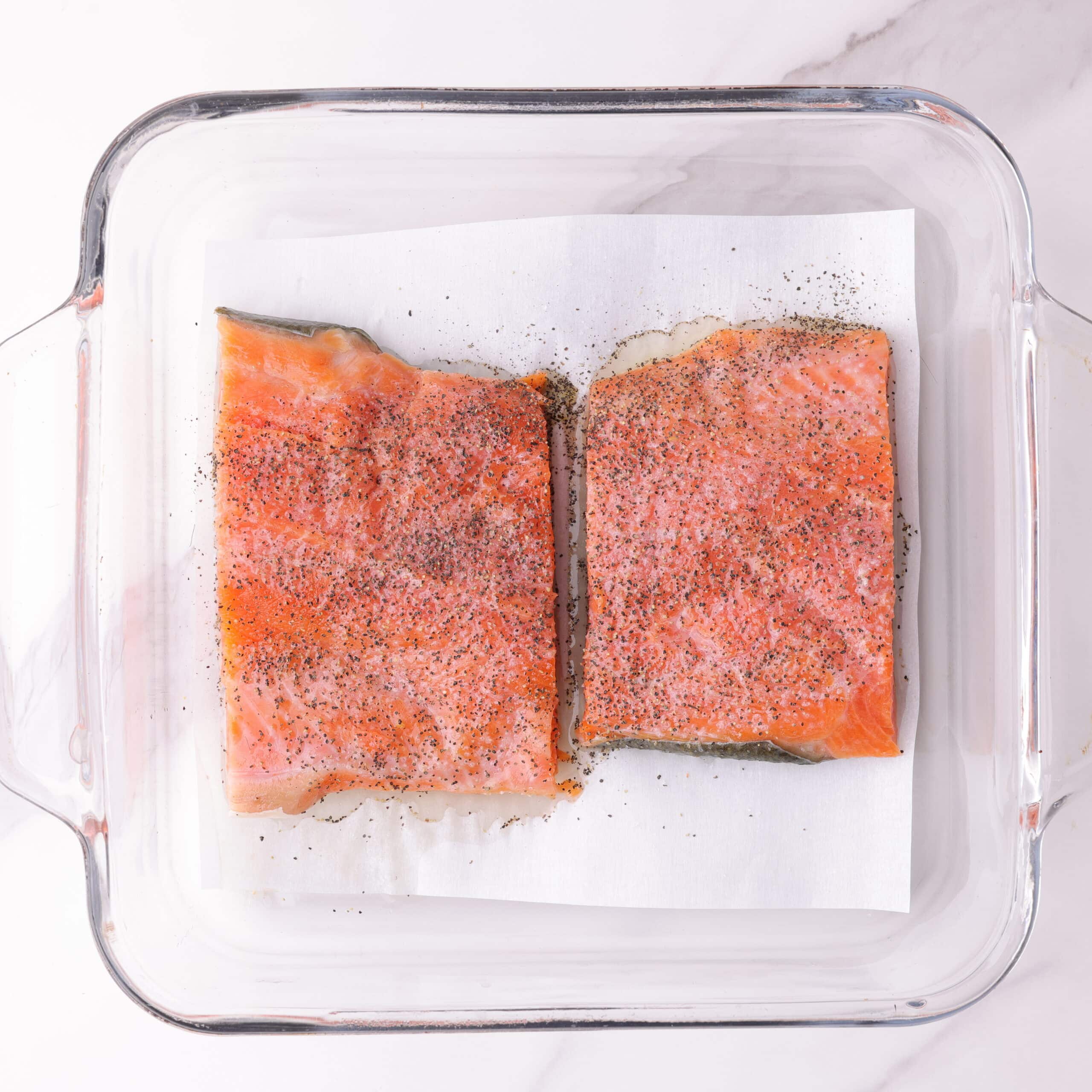 Two 3 ounce salmon fillets in baking dish, sprinkled with lemon juice and salt and pepper.