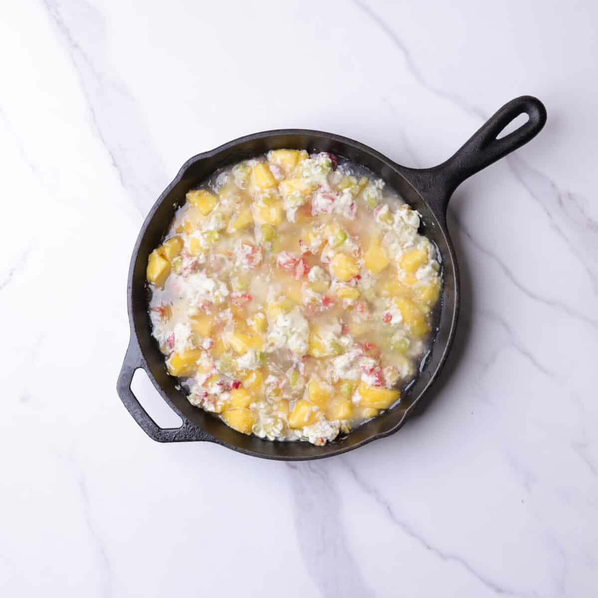 The skillet with the crumb base now topped with the fruit mixture and sugar syrup poured over top. 