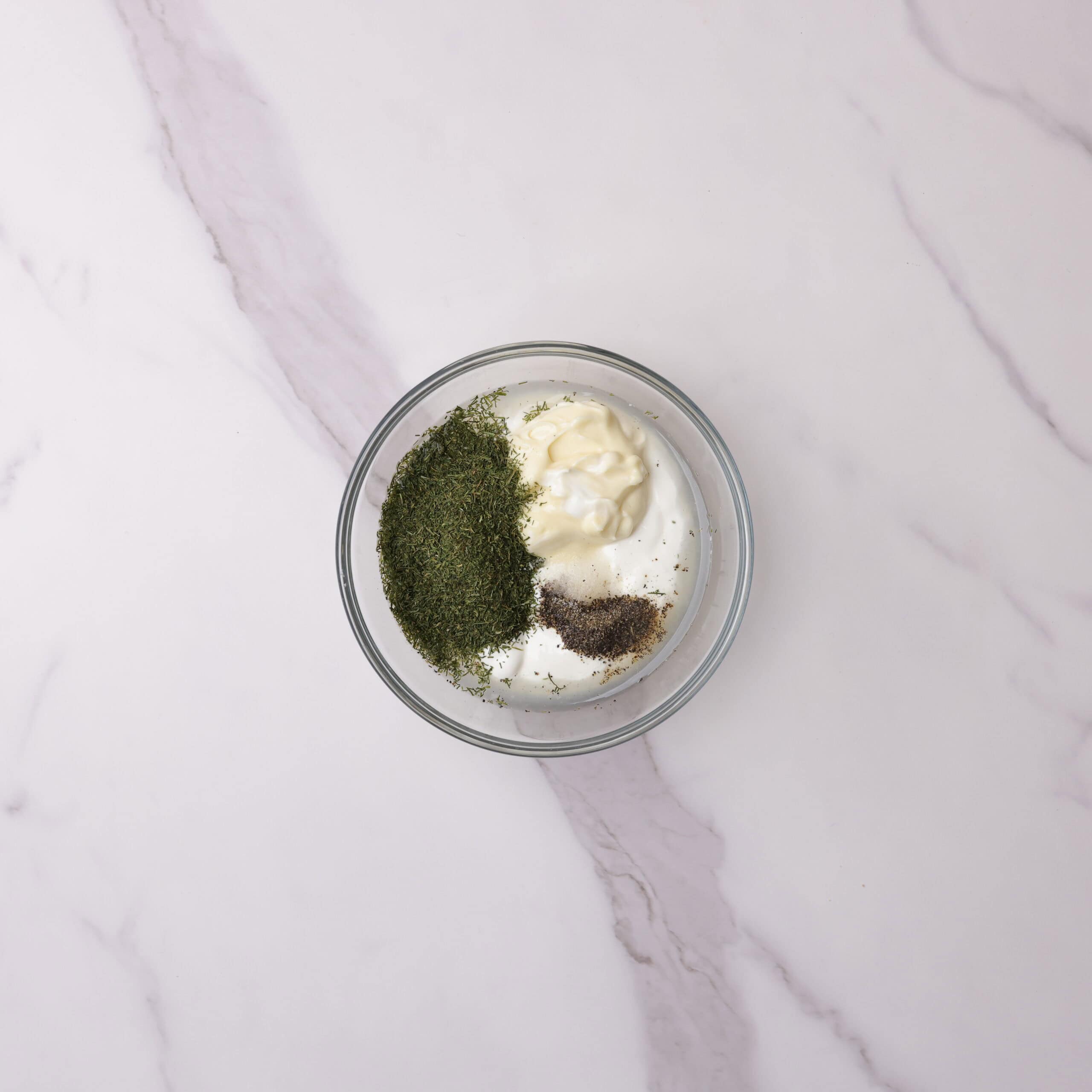 A small glass bowl with all the ingredients needed for the dill sauce. 