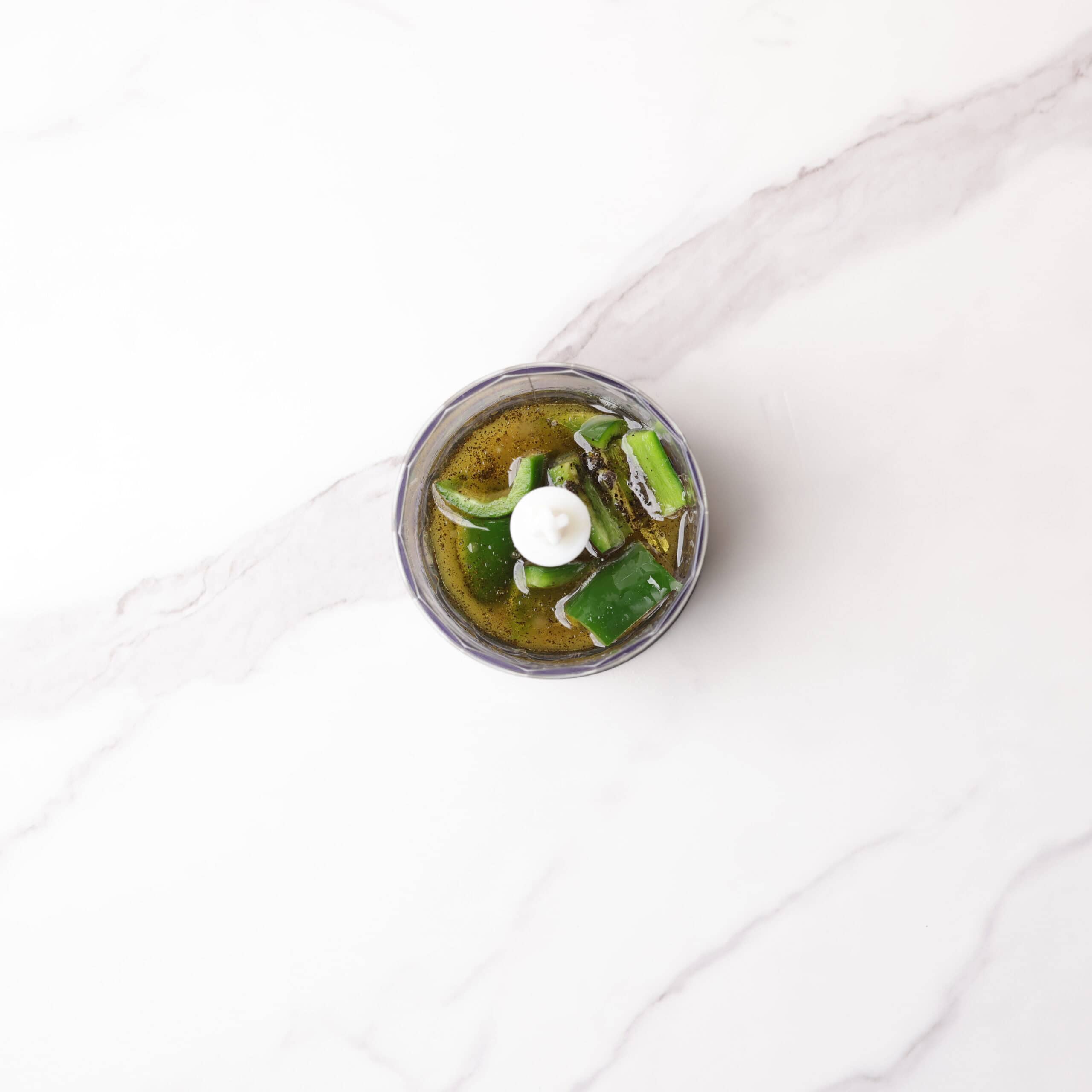 A small food processor filled with the ingredients for the dressing prior to blending.