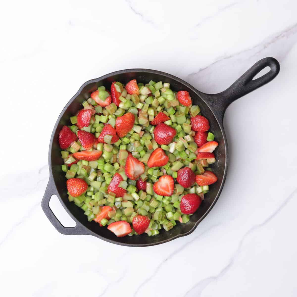 A cast iron skillet filled with the strawberry and rhubarb fruit mixture. 