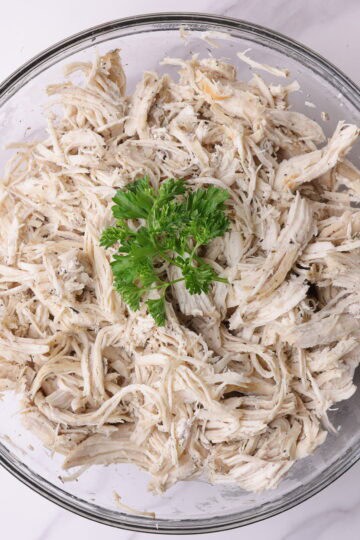 A bowl of "Shredded Chicken Instant Pot" garnished with parsley.