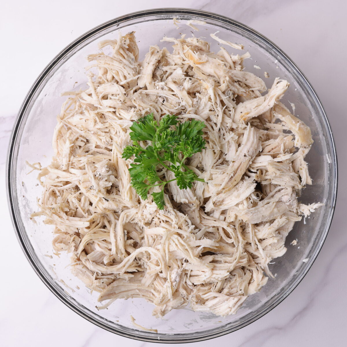 A bowl of "Shredded Chicken Instant Pot" garnished with parsley.