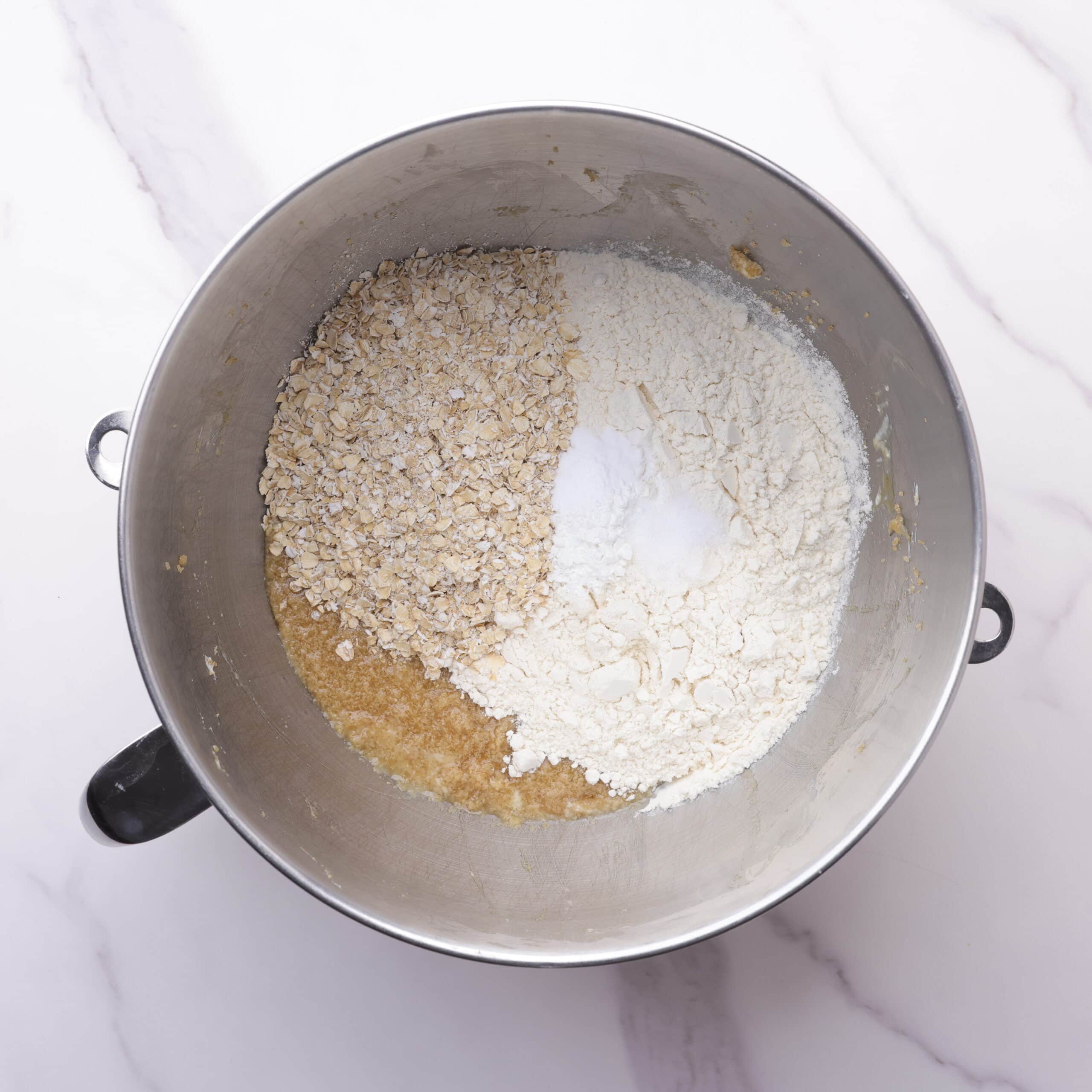 A mixing bowl with the dry ingredients on top of the butter mixture.