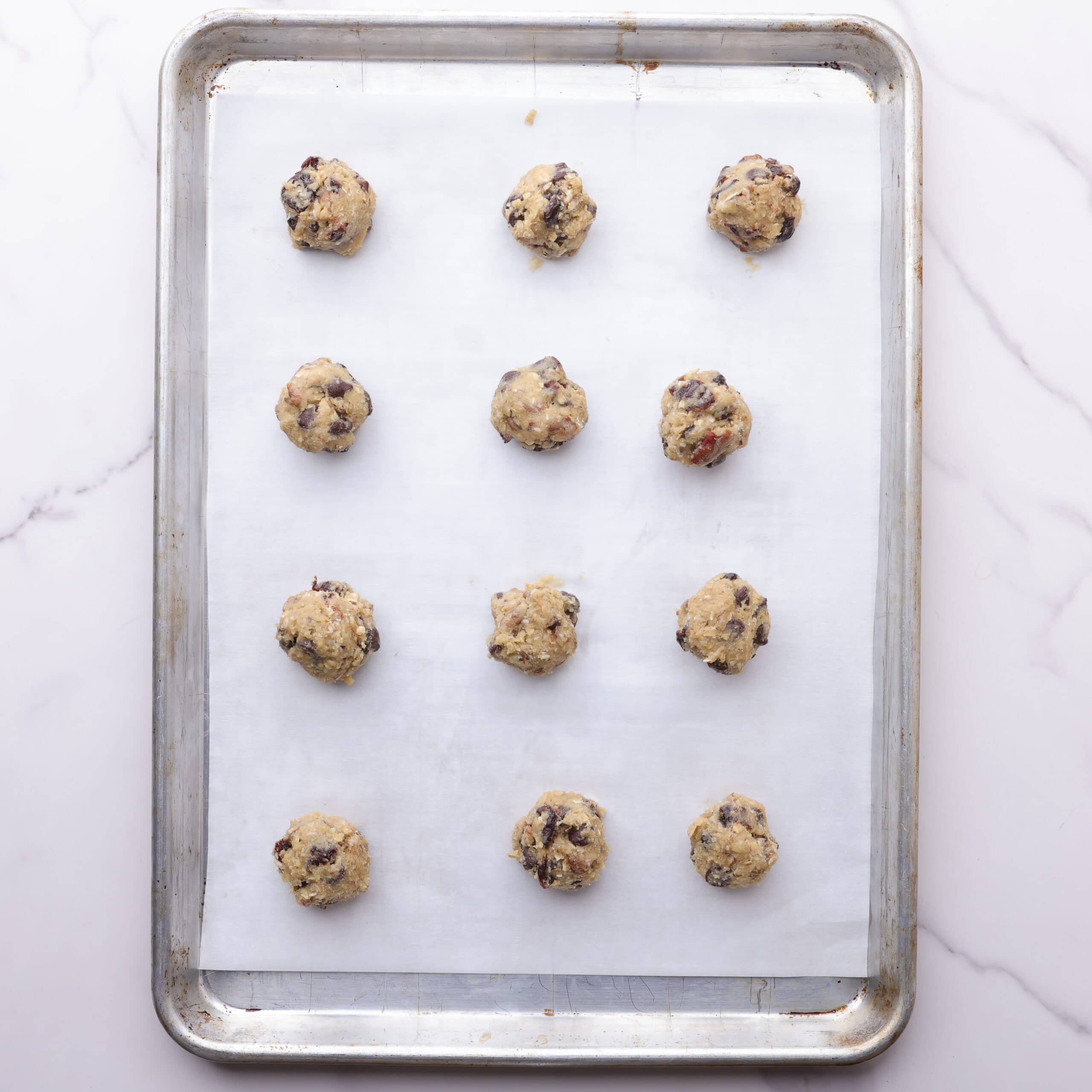 A cookie sheet with 12 cookies scooped onto it, ready to bake.