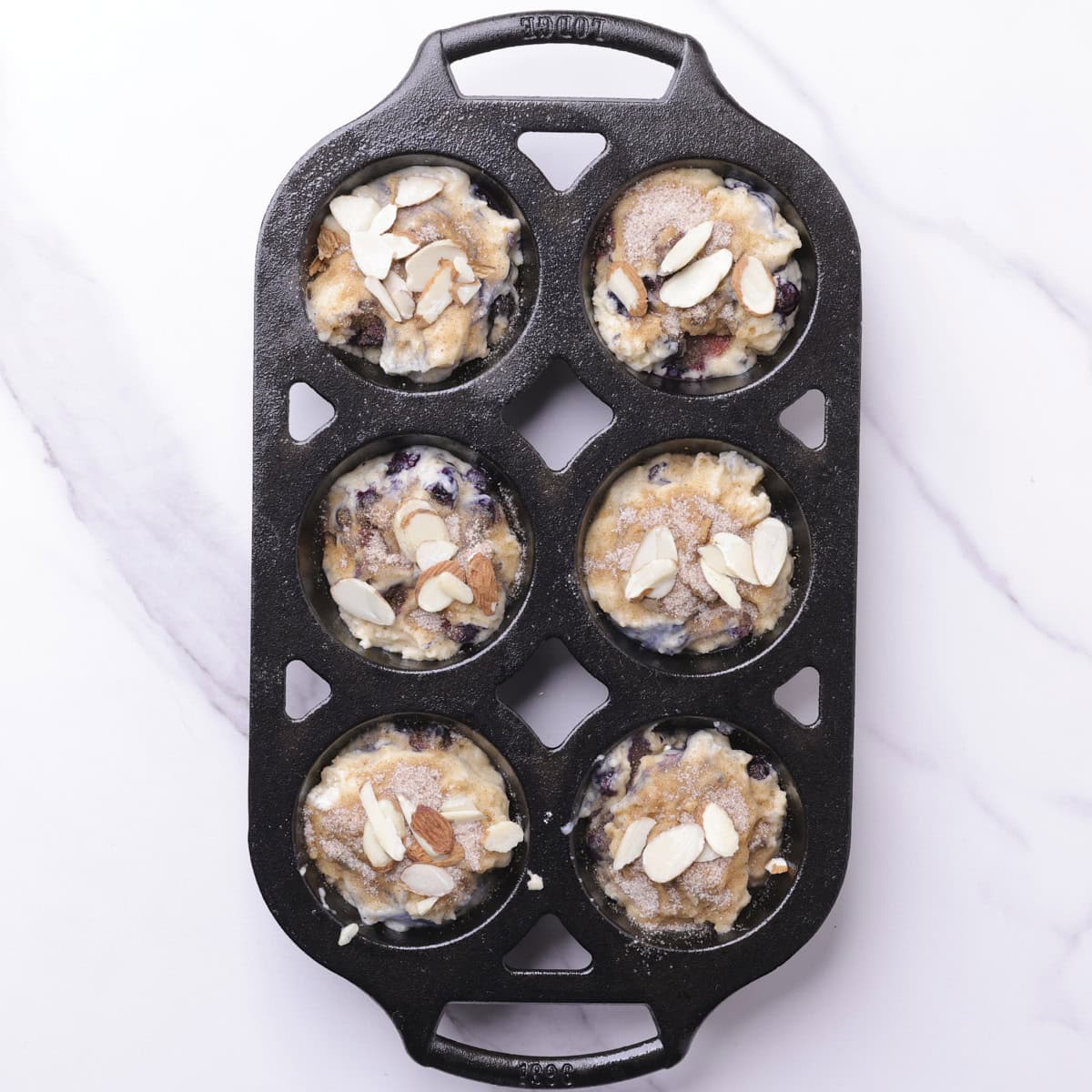 The blueberry muffins in the cast iron muffin tins topped with cinnamon sugar and slivered almonds.