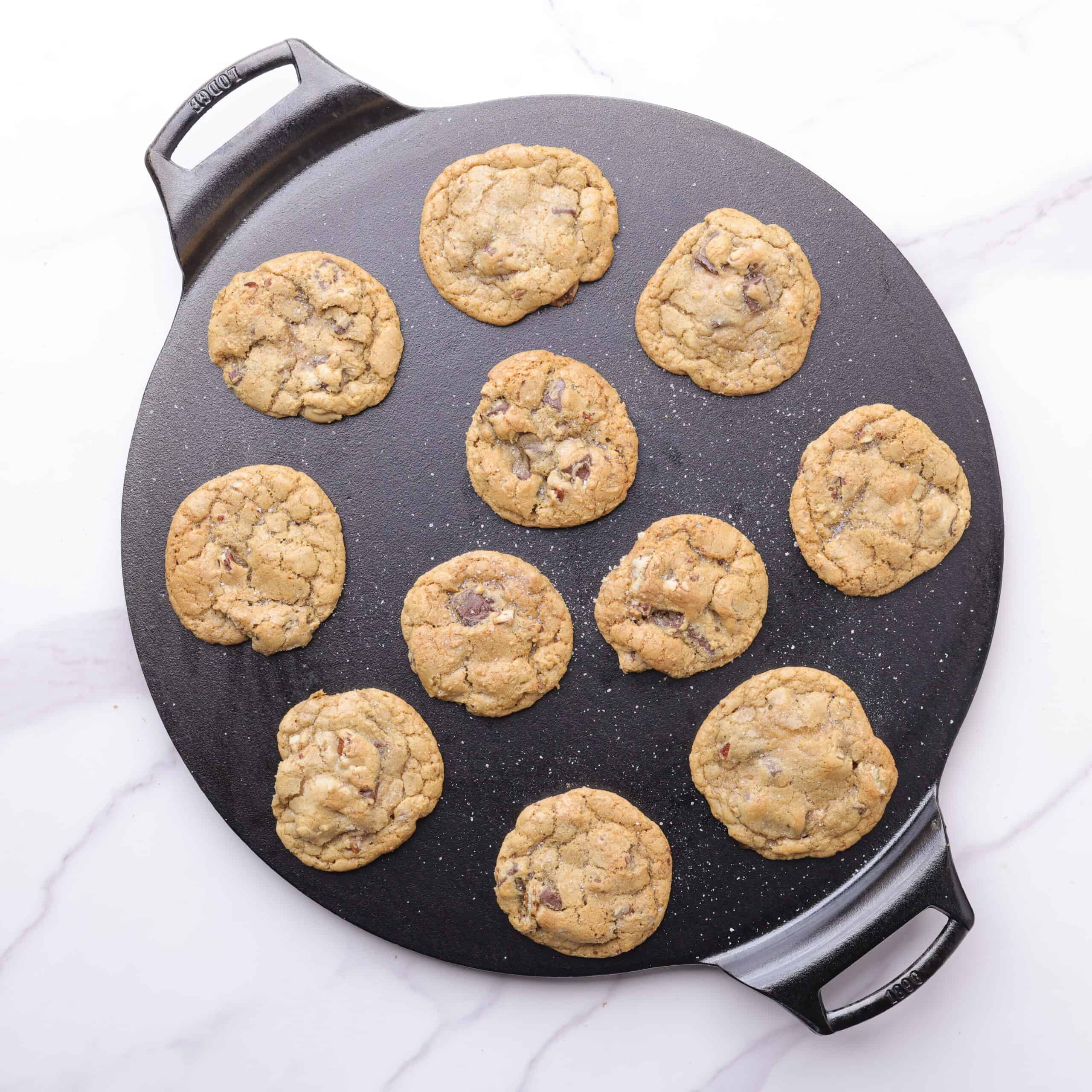 A cast iron baking pan with chocolate chunk pecan cookies baked to perfection on it.