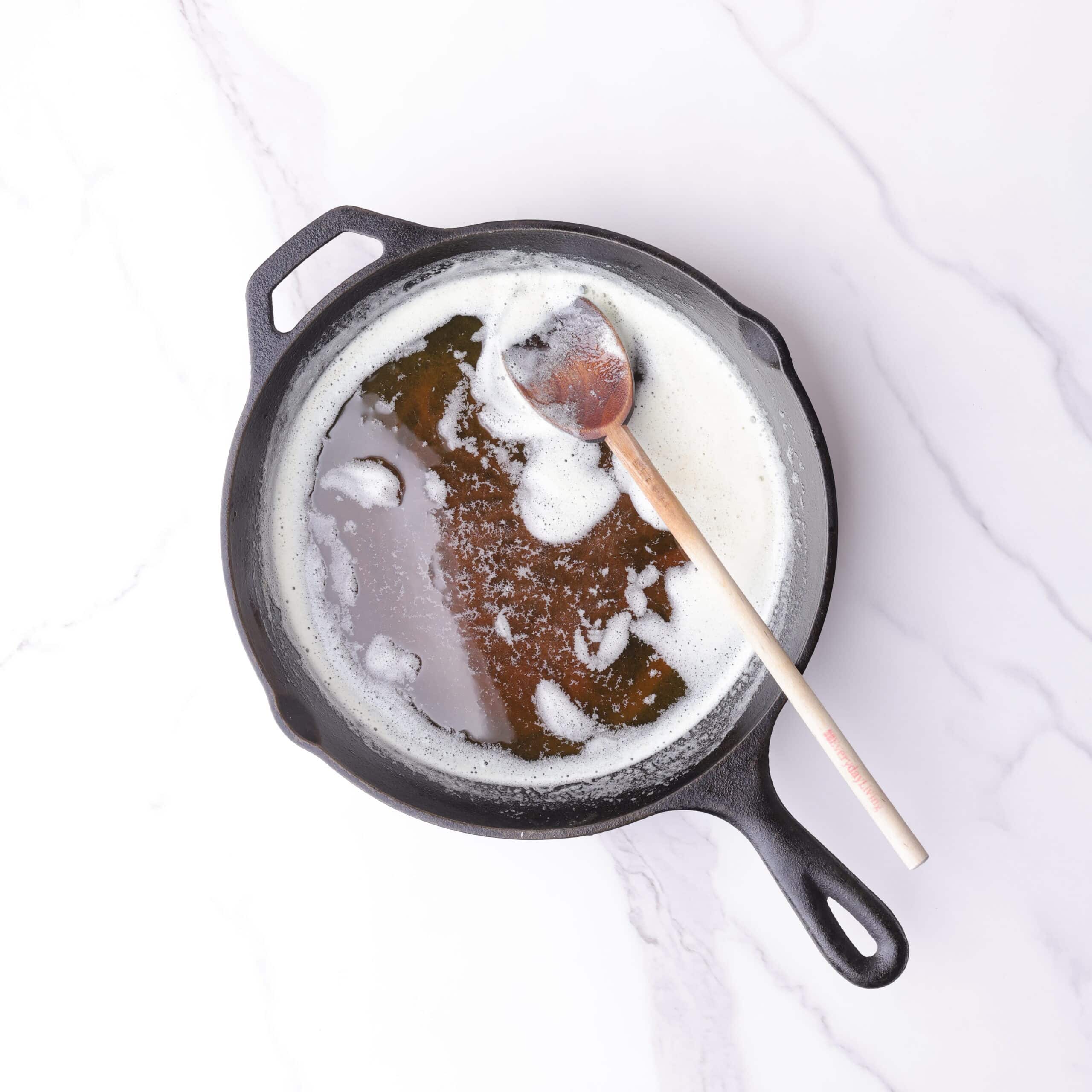 A skillet with browned butter in it and a wooden spoon for stirring