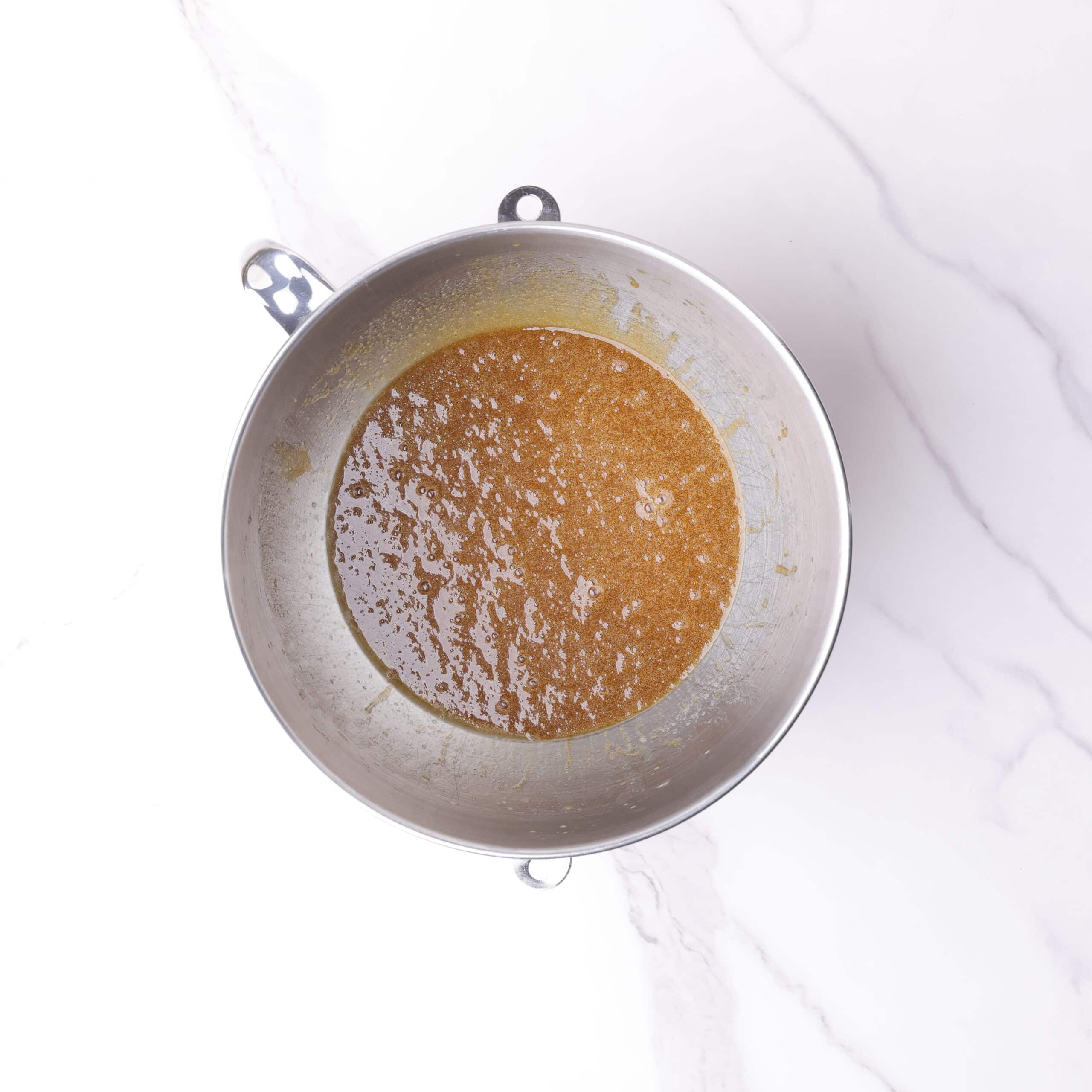 A mixing bowl with the sugars and liquid ingredients combined in it.