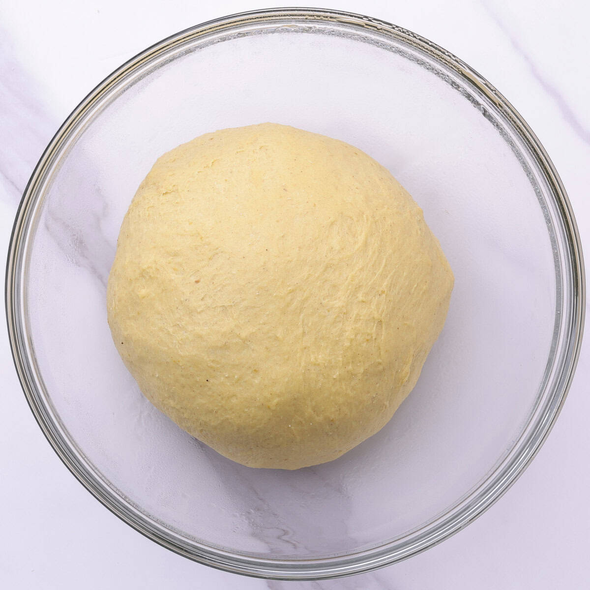 A lightly oiled glass bowl with the ball shaped dough in it, ready to rise.