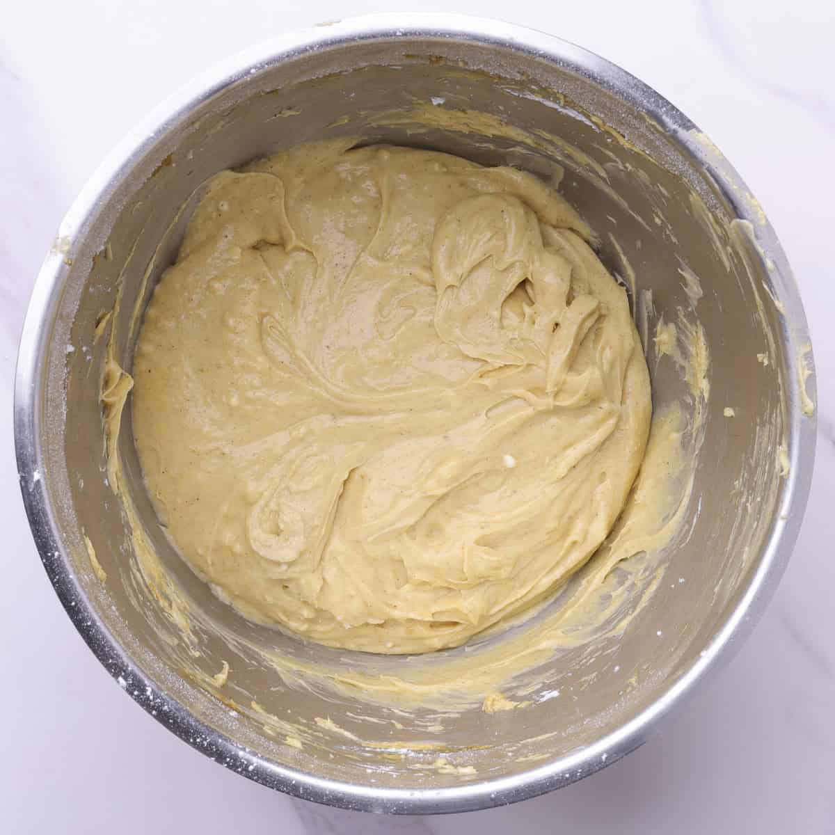 A mixing bowl with the finished pumpkin cream cheese frosting in it.