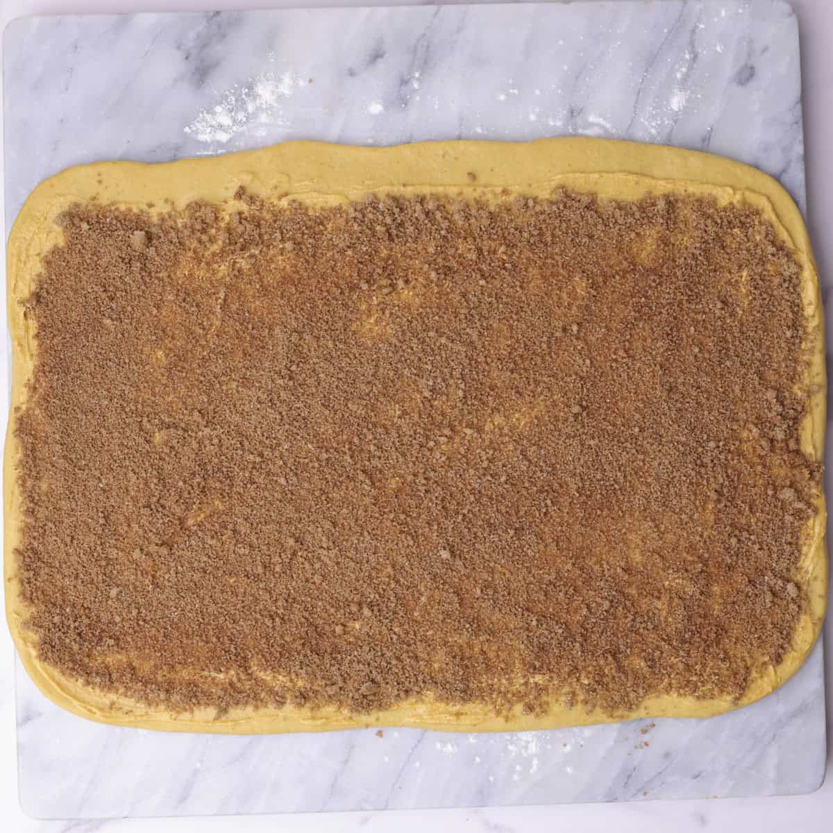 The pumpkin cinnamon roll dough rolled into a rectangle and topped with the pumpkin butter and spiced sugar mixture.