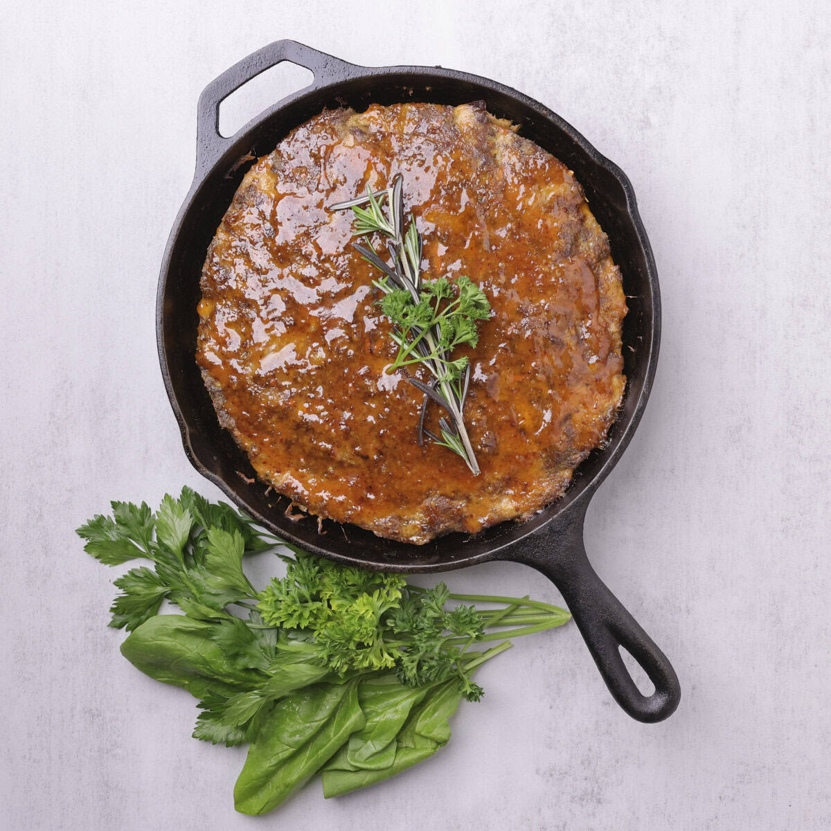 The baked Skillet Meatloaf, topped with the honey-Dijon sauce and garnished with rosemary and parsley.