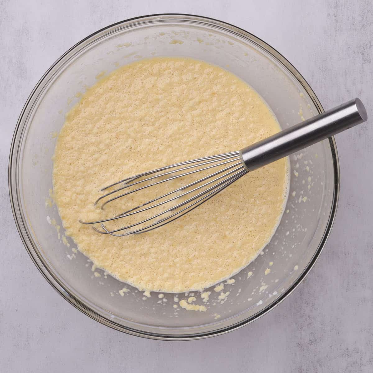 The breadcrumb and milk mixture in a glass bowl with a whisk.