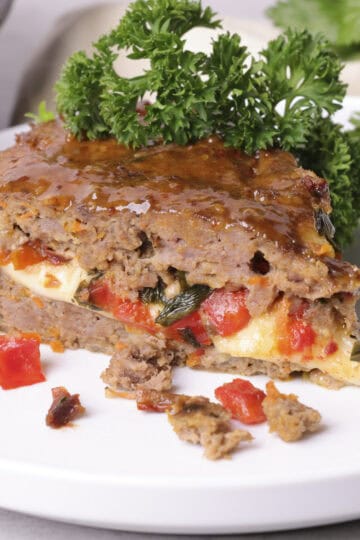 A slice of the Skillet Meatloaf on a white plate, garnished.