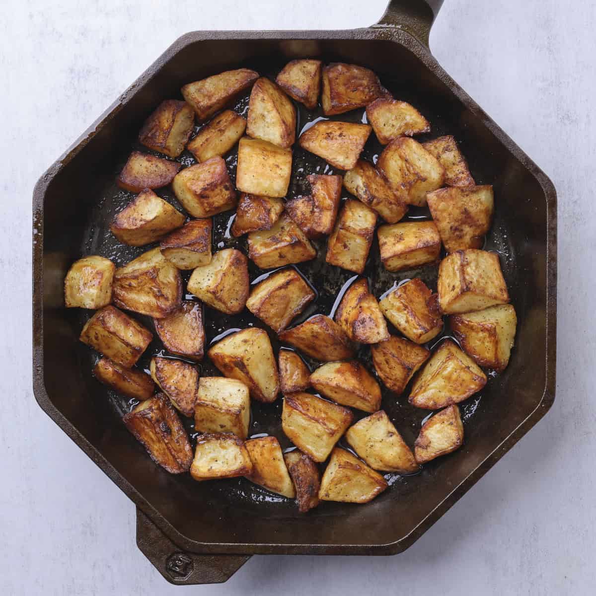 A skillet with the Baked Home Fries baked to golden brown.