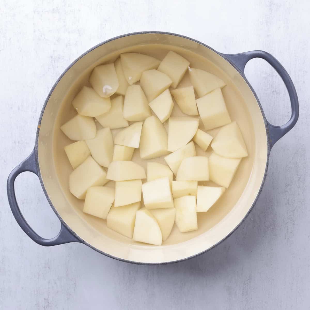Peeled and cut potatoes in a cast iron pot, covered with water.