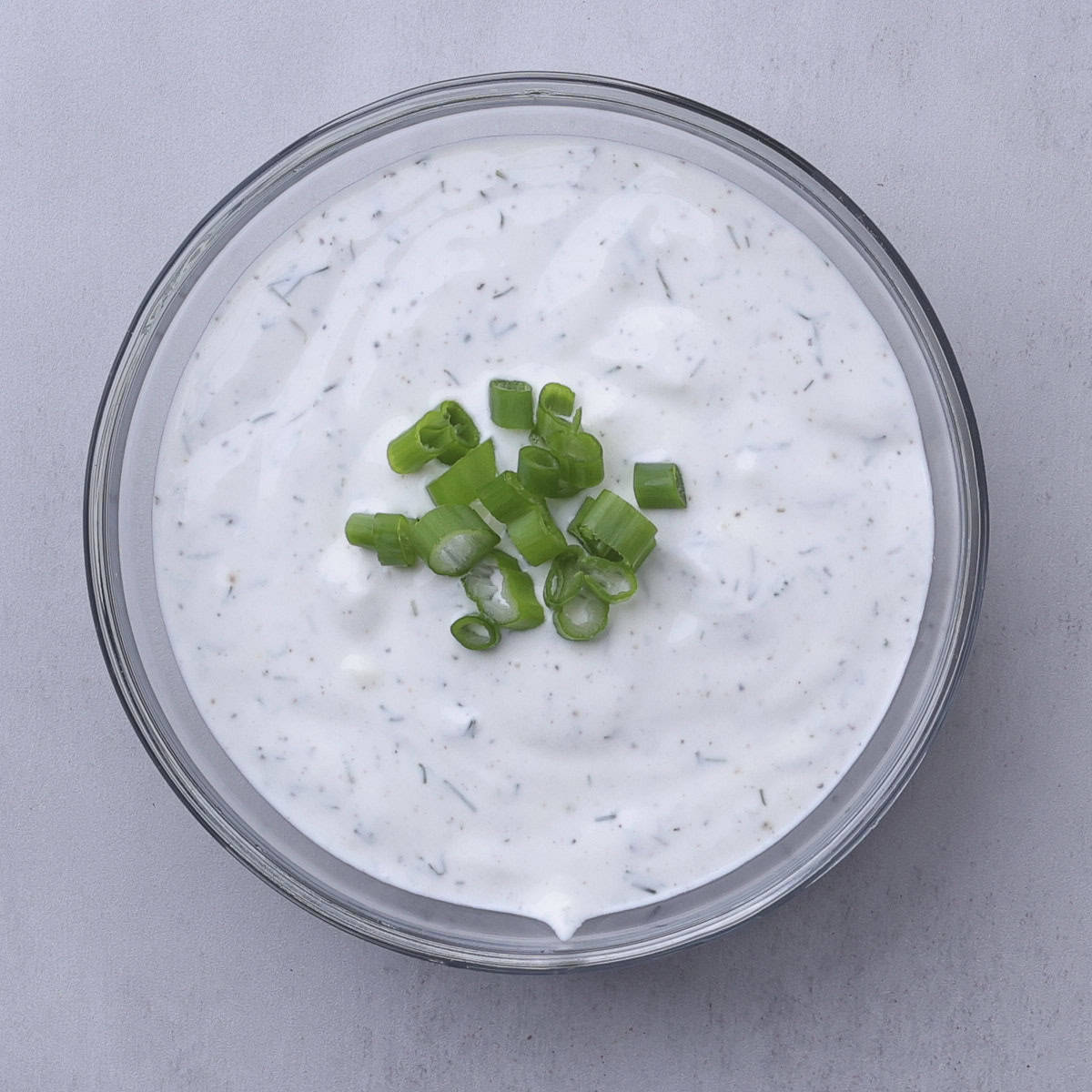 A bowl of mixed dill dip garnished with green onions.