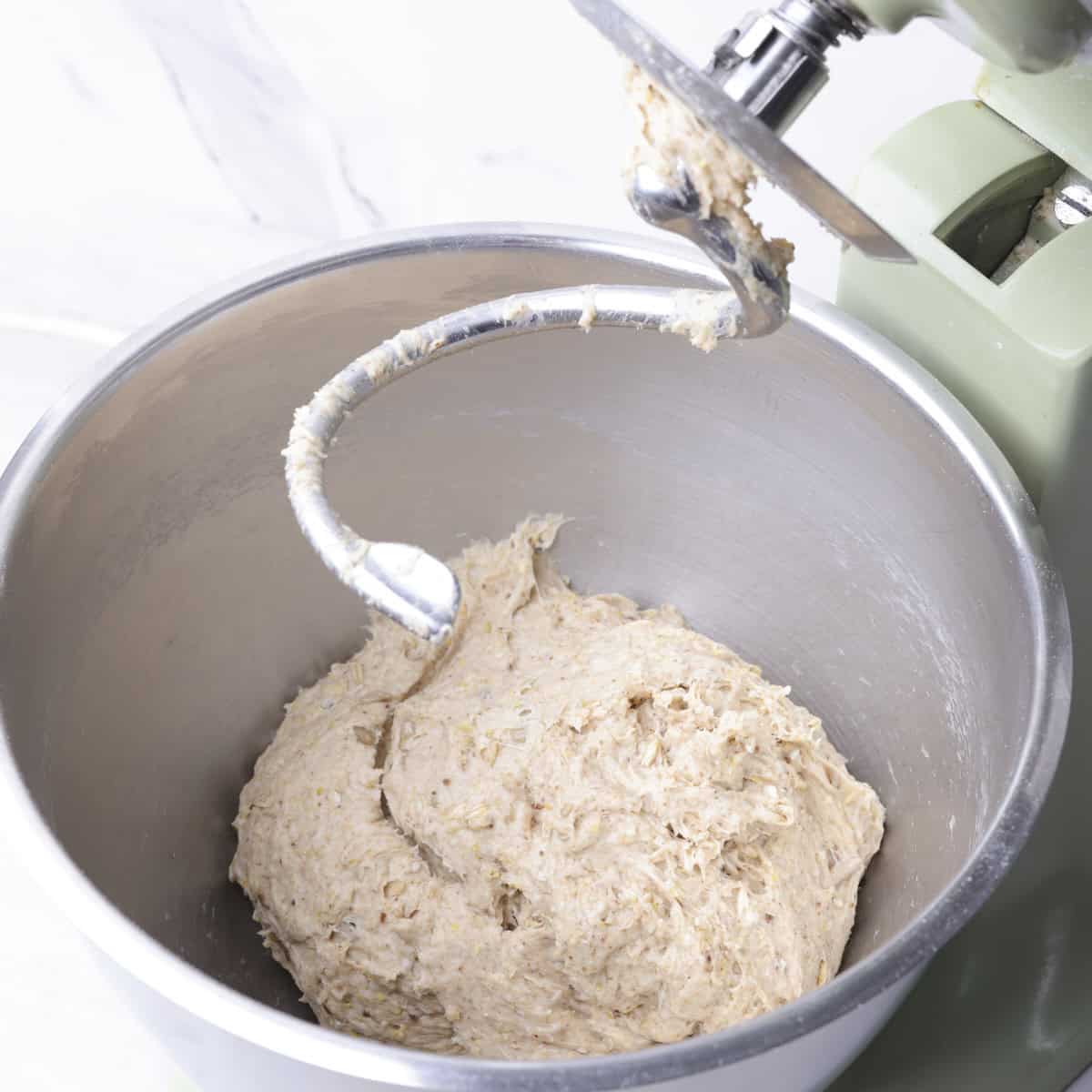 The stand mixer with the hook lifted and the dough combined in the bowl.