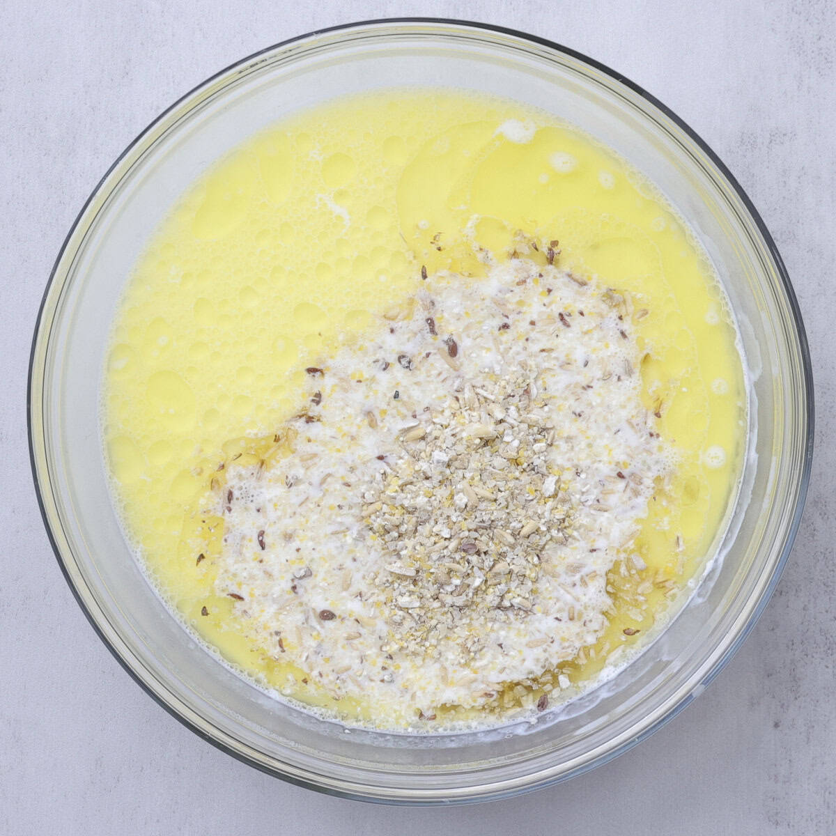 A glass bowl with the milk and melted butter with the 7 grain cereal mix soaking.