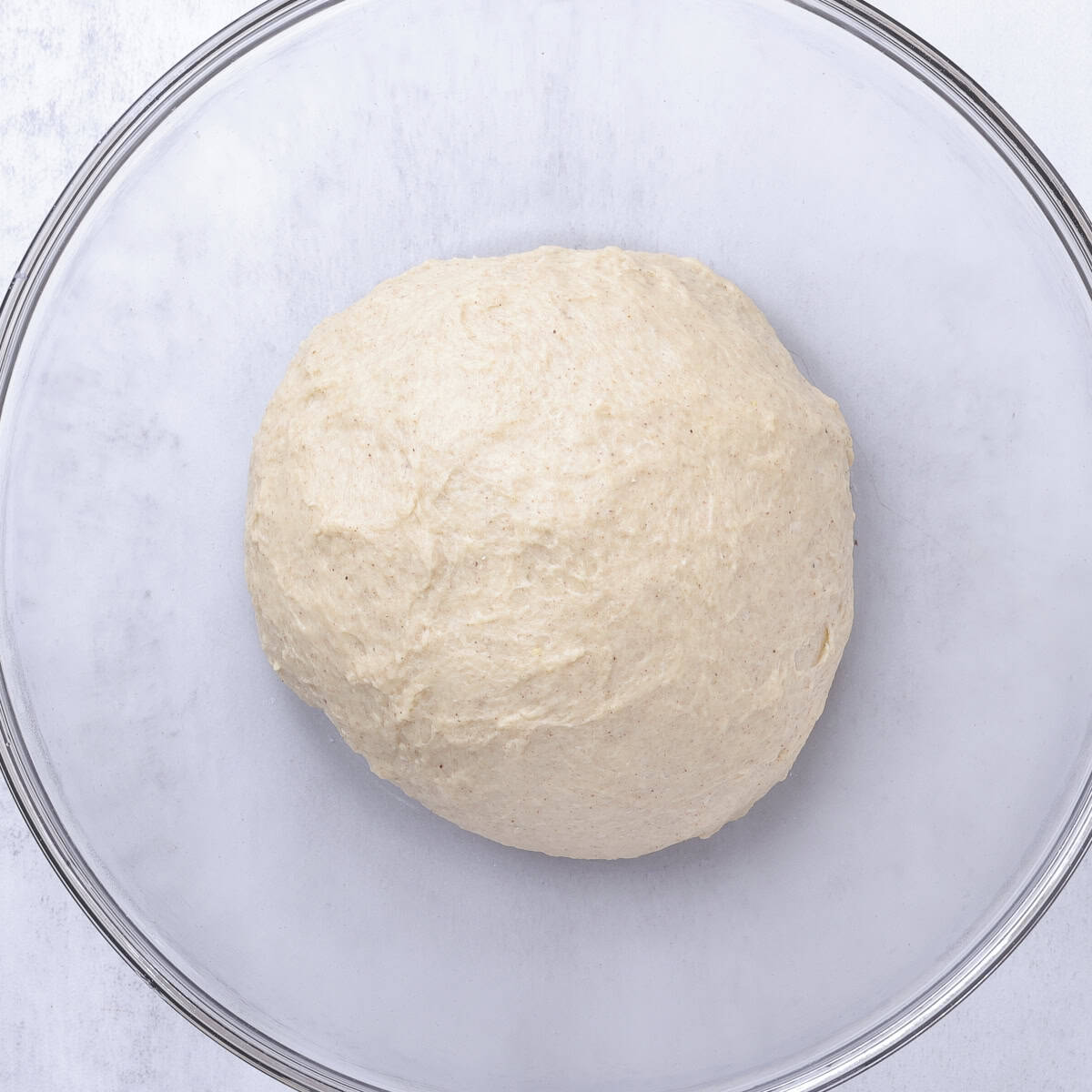 The dough formed into a round ball and placed in a glass bowl to rise.