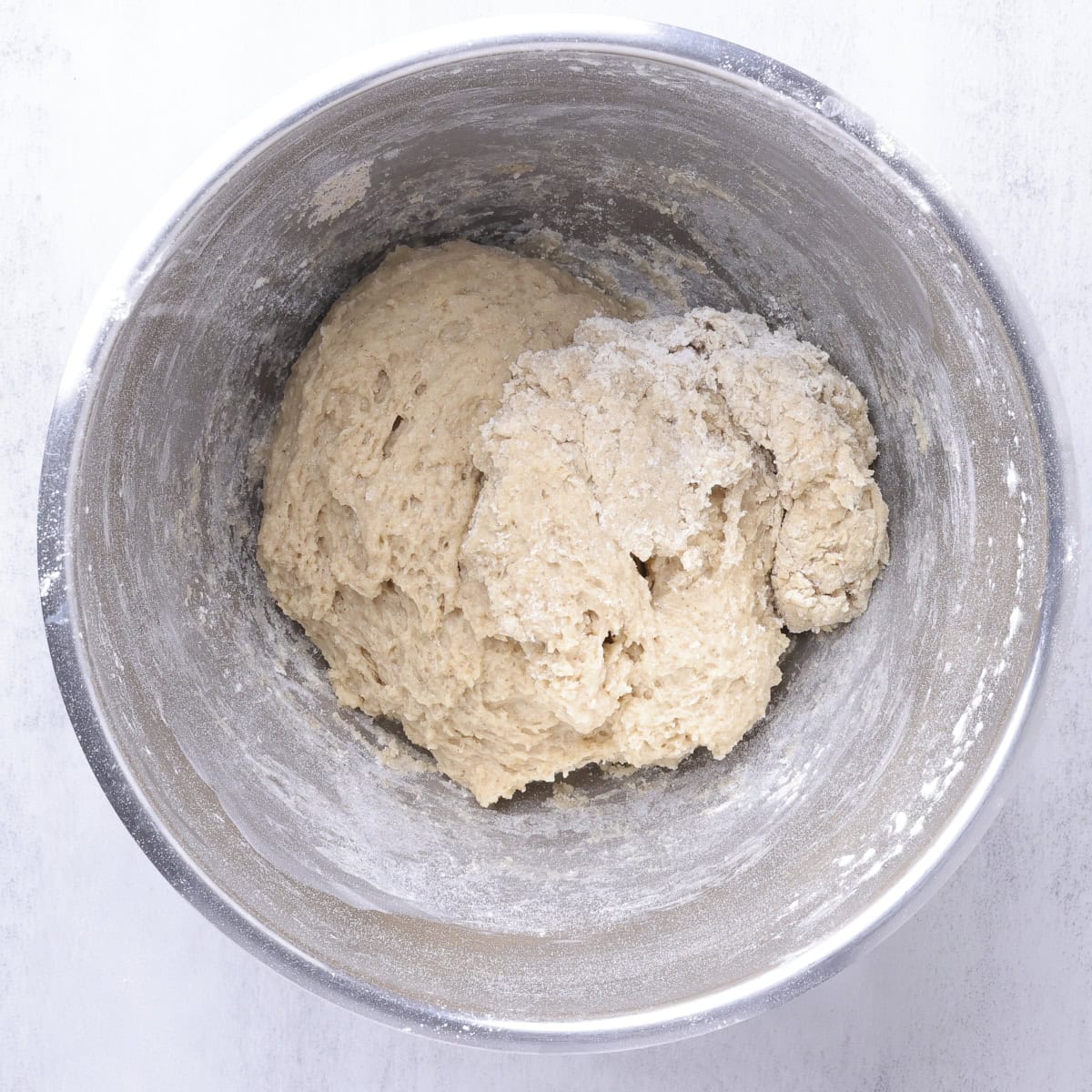 A mixing bowl with a rough dough formed in it.