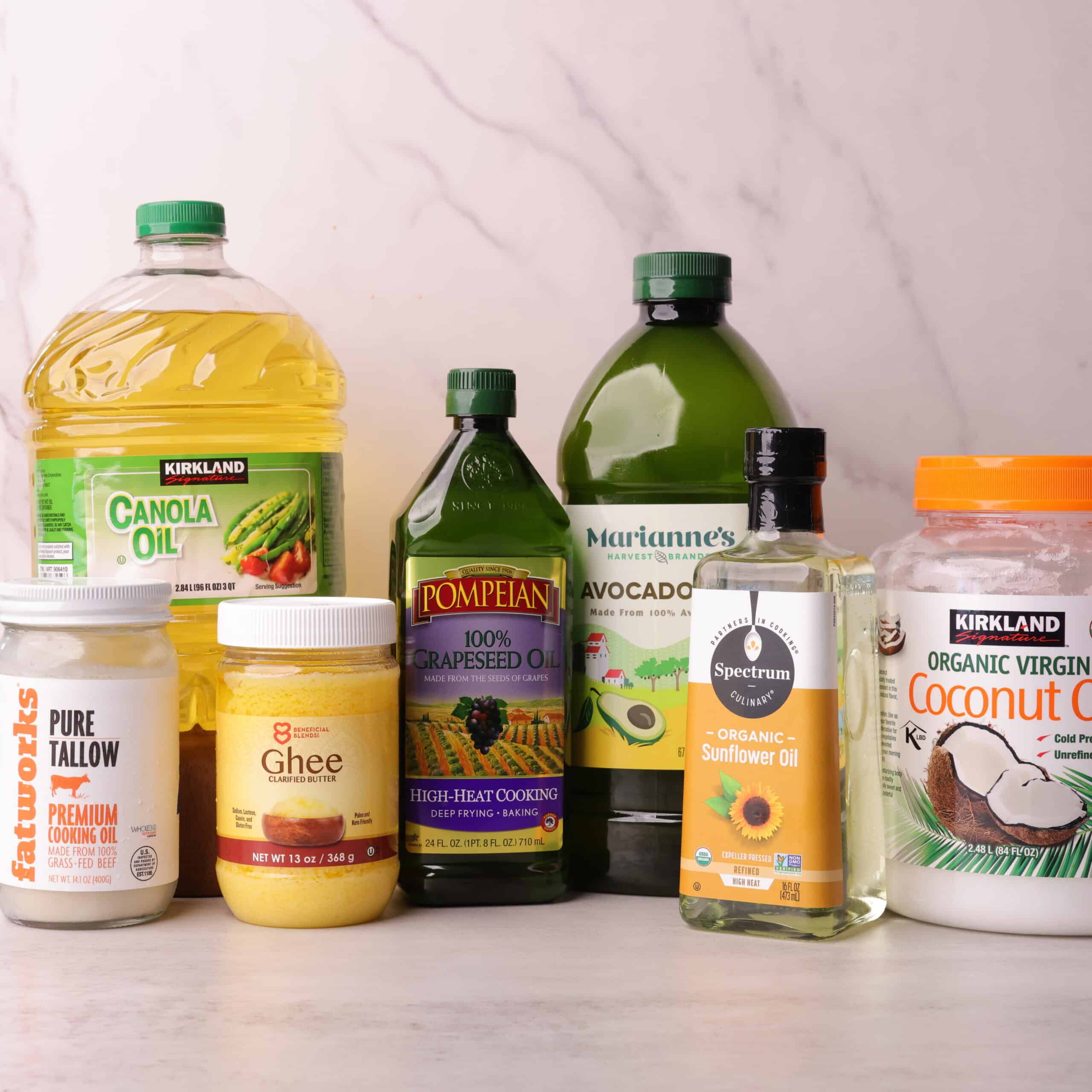 A compilation of high-smoke point oils - canola, beef tallow, ghee, grapeseed, avocado, sunflower and coconut oil.