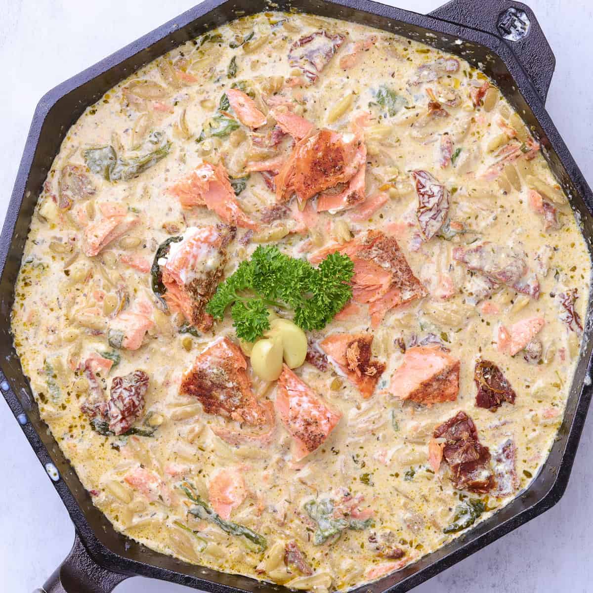 A skillet with the finished Salmon Pasta in it, garnished with parsley.