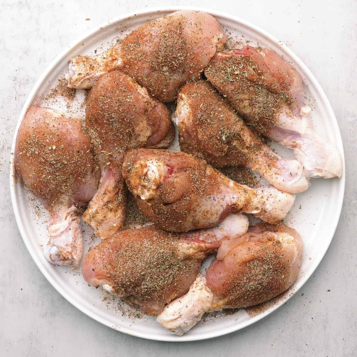 A plate of seasoned raw drumsticks.