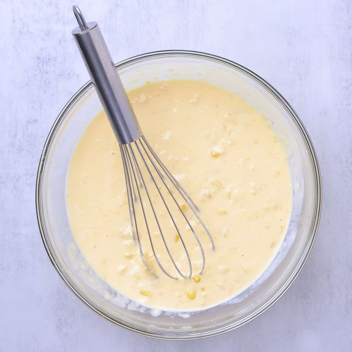 A bowl of the wet ingredients with a whisk in it.