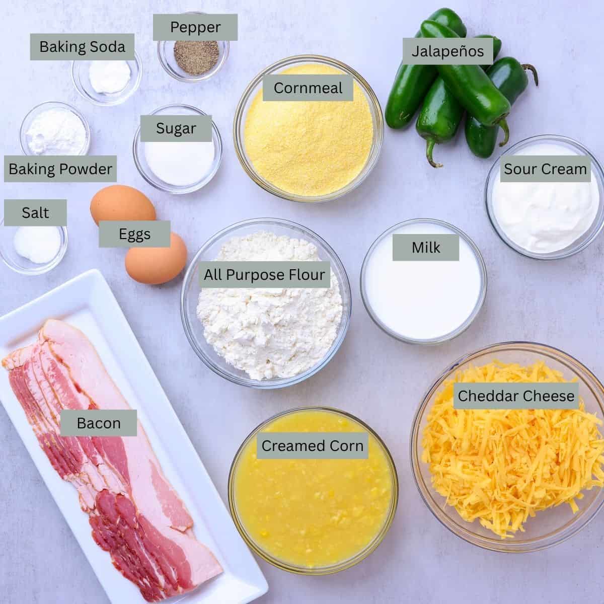 A visual display of the ingredients needed for the Cheddar Cheese Jalapeno Cornbread - pepper, salt, baking soda, baking powder, sugar, eggs, bacon, creamed corn, cheddar cheese, milk, flour, sour cream, cornmeal and jalapenos.