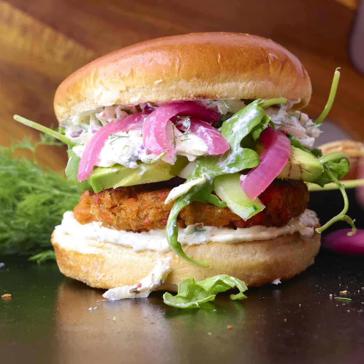 A Salmon Burger with Canned Salmon with toppings on a cast iron platter.