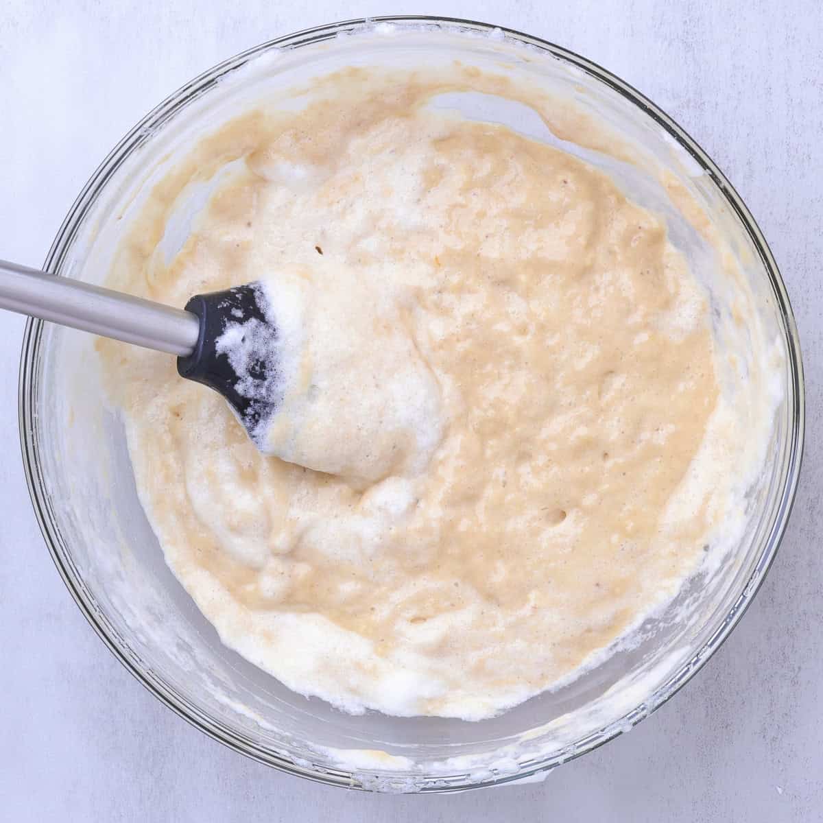 A glass bowl with the egg whites folded into the batter but not fully combined. 