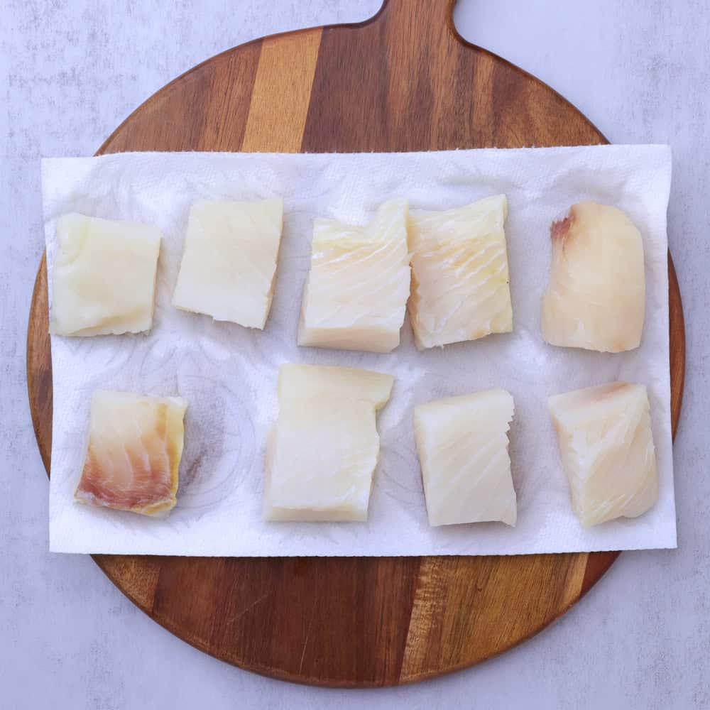 Chunks of halibut set out on paper towel to dry out.