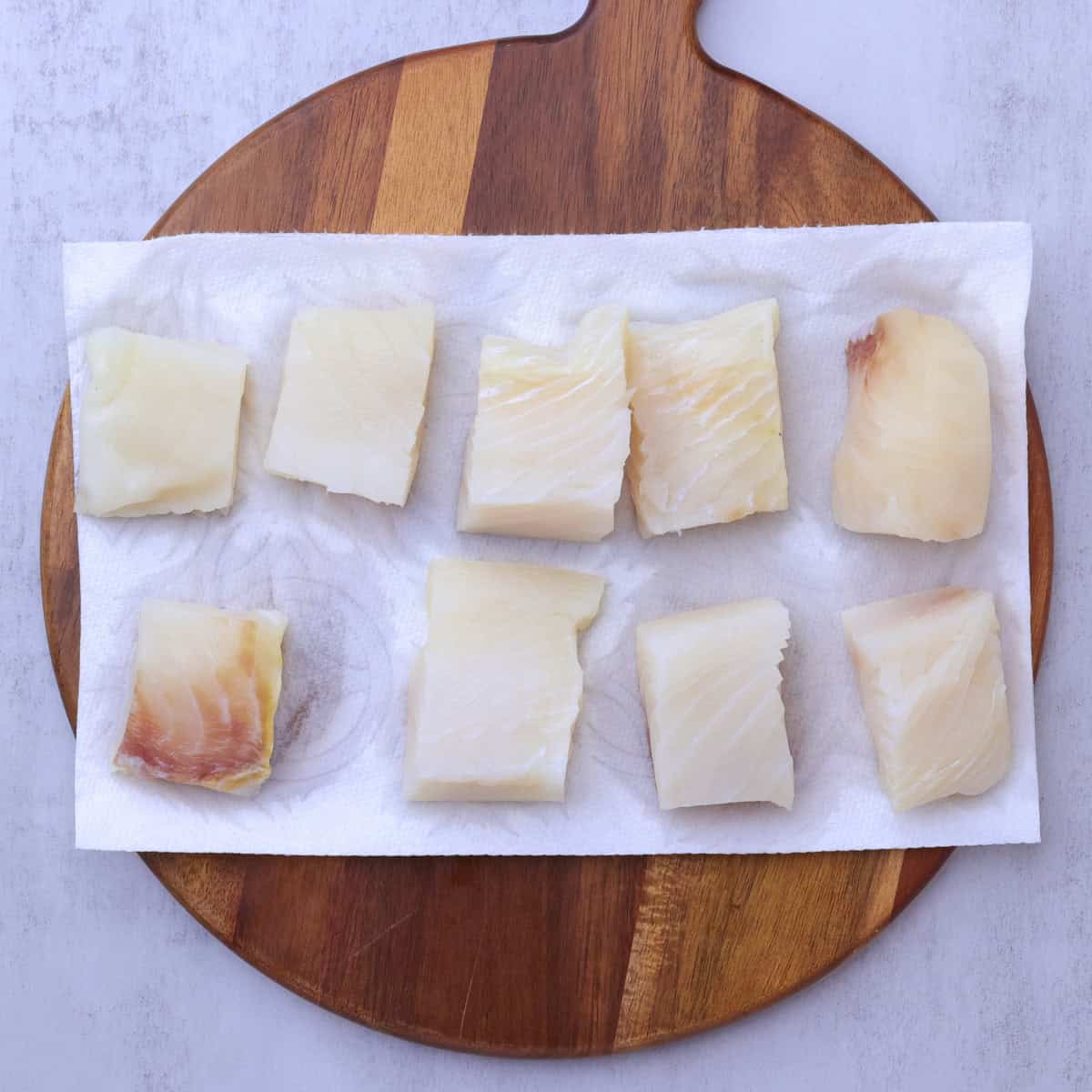 Chunks of halibut set out on paper towel to dry out.