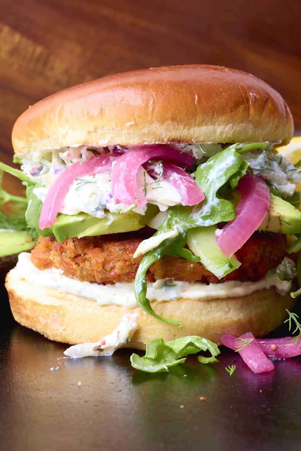 Close-up of Alaskan Skillet fish sandwich with fresh vegetables and bun.