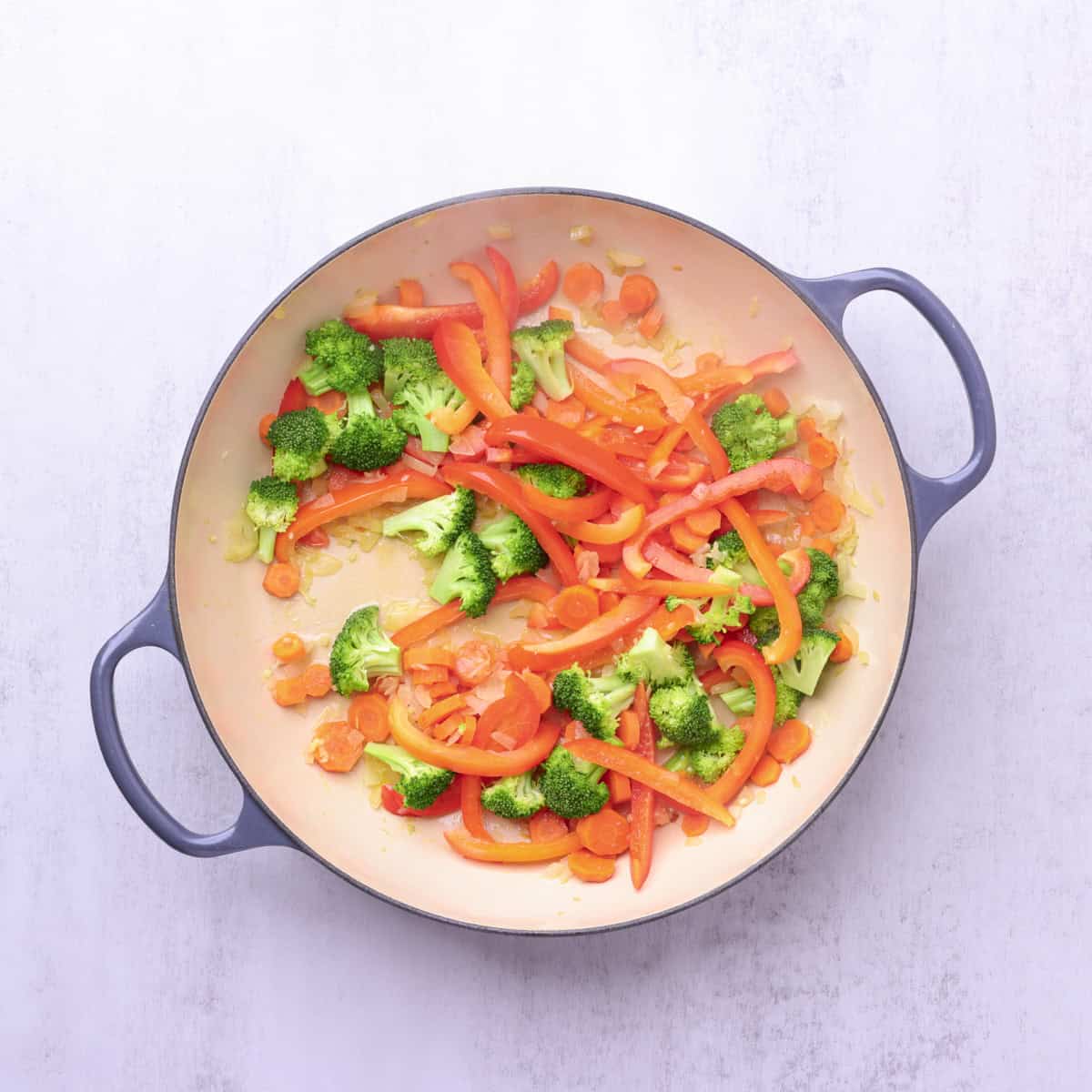 The broccoli, red bell peppers, and carrots added to the sauteed onions and garlic.