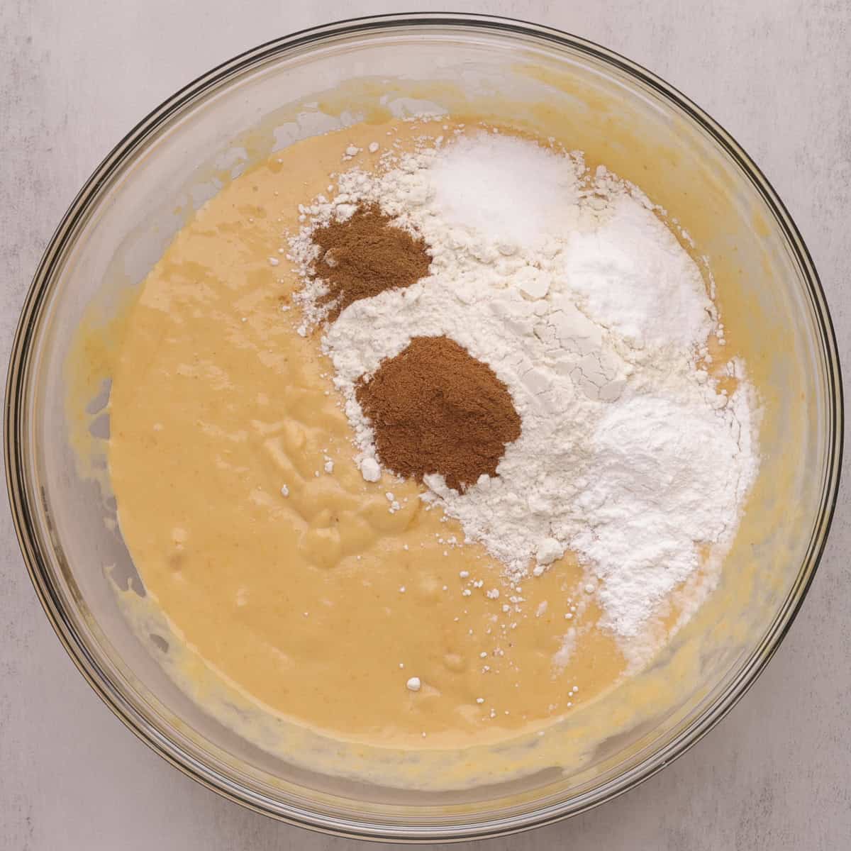 A glass bowl with the mixed batter topped with the dry ingredients.