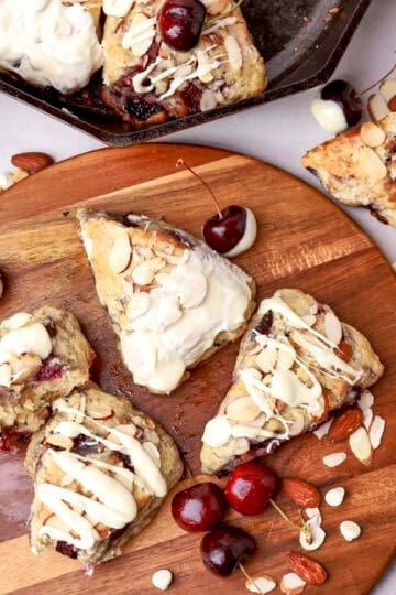 An overhead view of the Cherry Scones displayed on a wooden board with nuts and cherries sprinkled around.