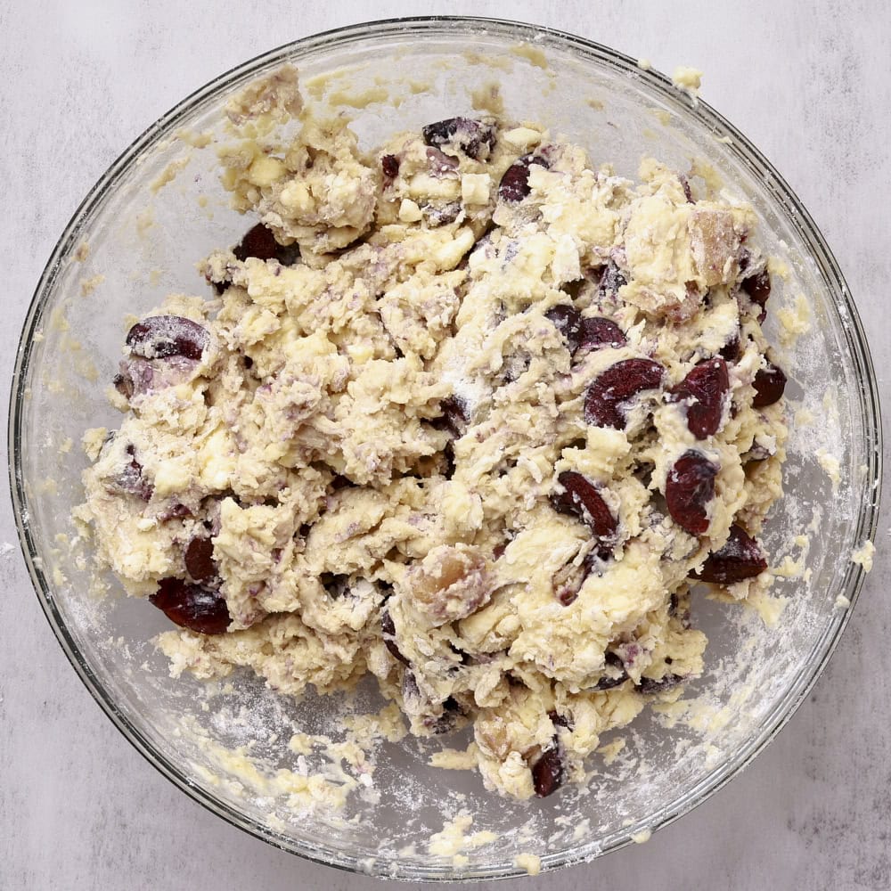 A bowl filled with wet, shaggy cherry scone batter.