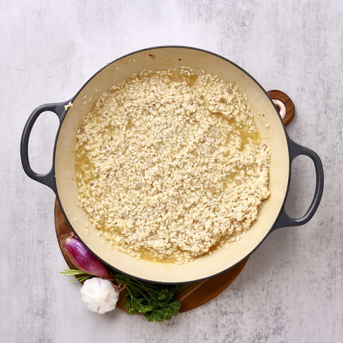 A large pan with the rice partially cooked and chicken broth added.