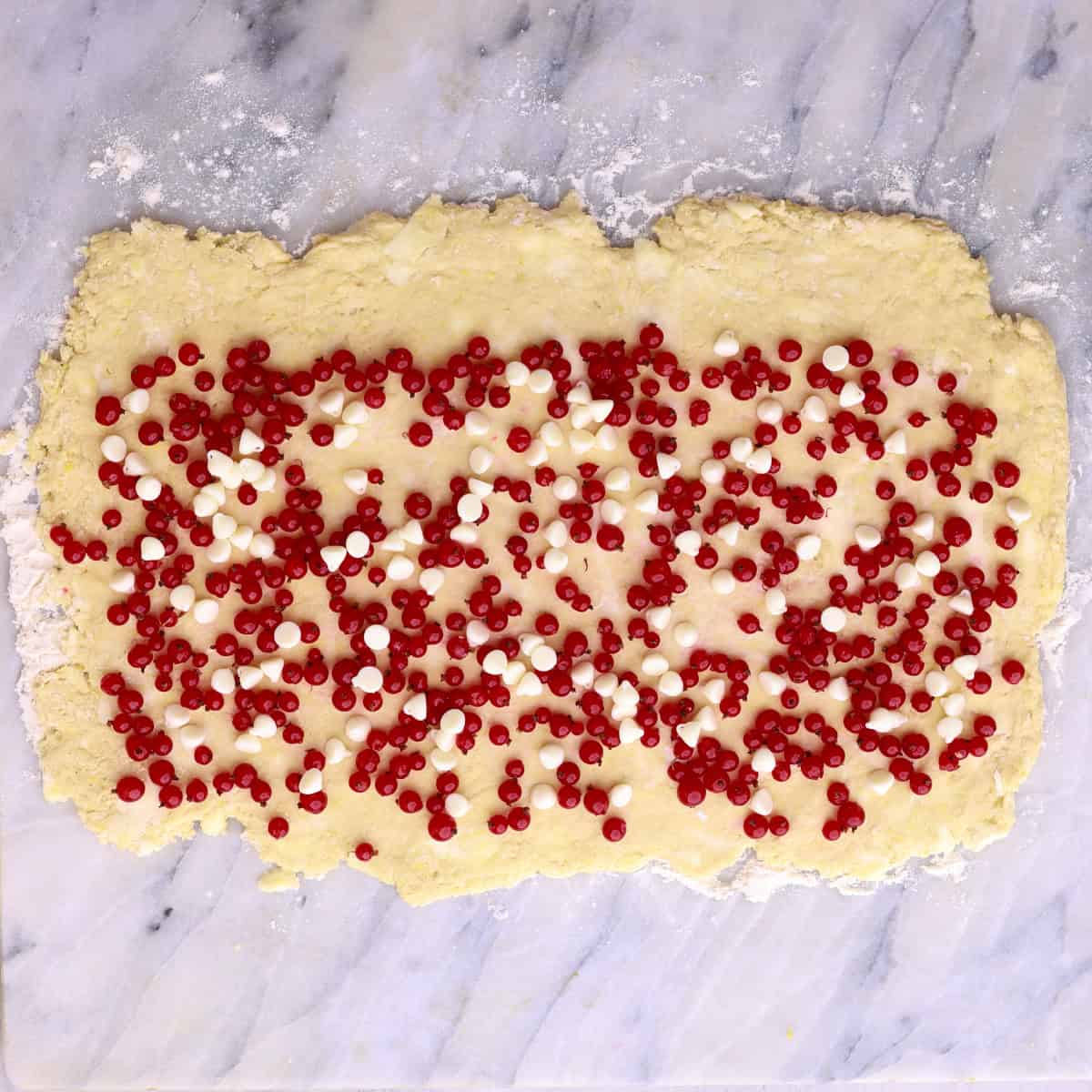The scone dough rolled out into a rectangle and sprinkled with currants and white chocolate chips.