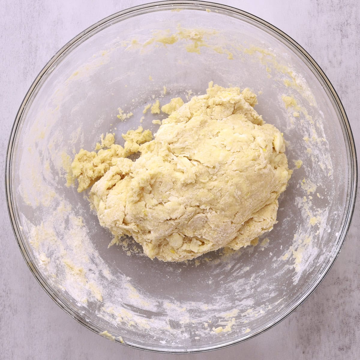 A glass bowl with a ball of shaggy dough.
