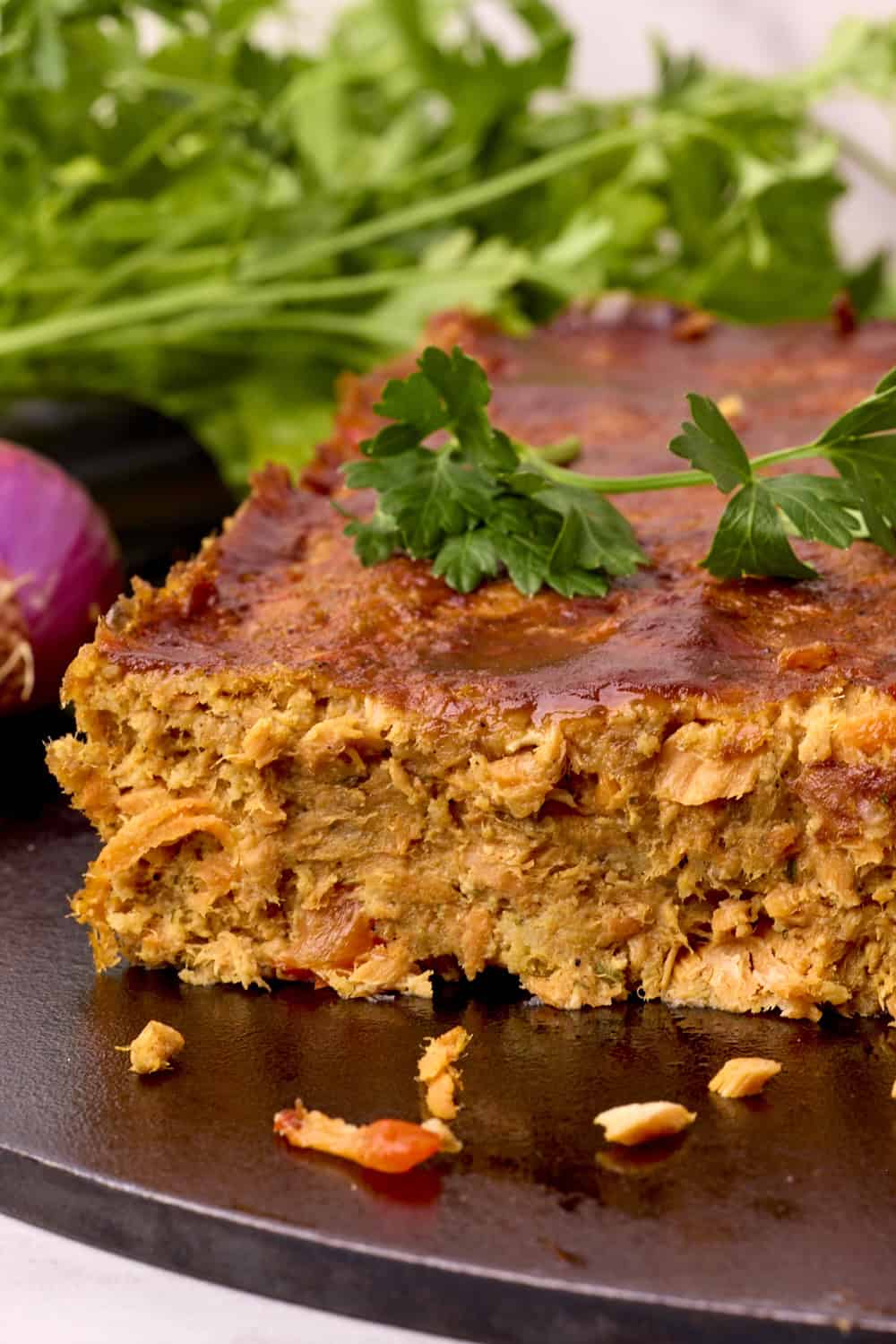 An open faced Salmon Loaf displayed on a cast iron pan with greens.