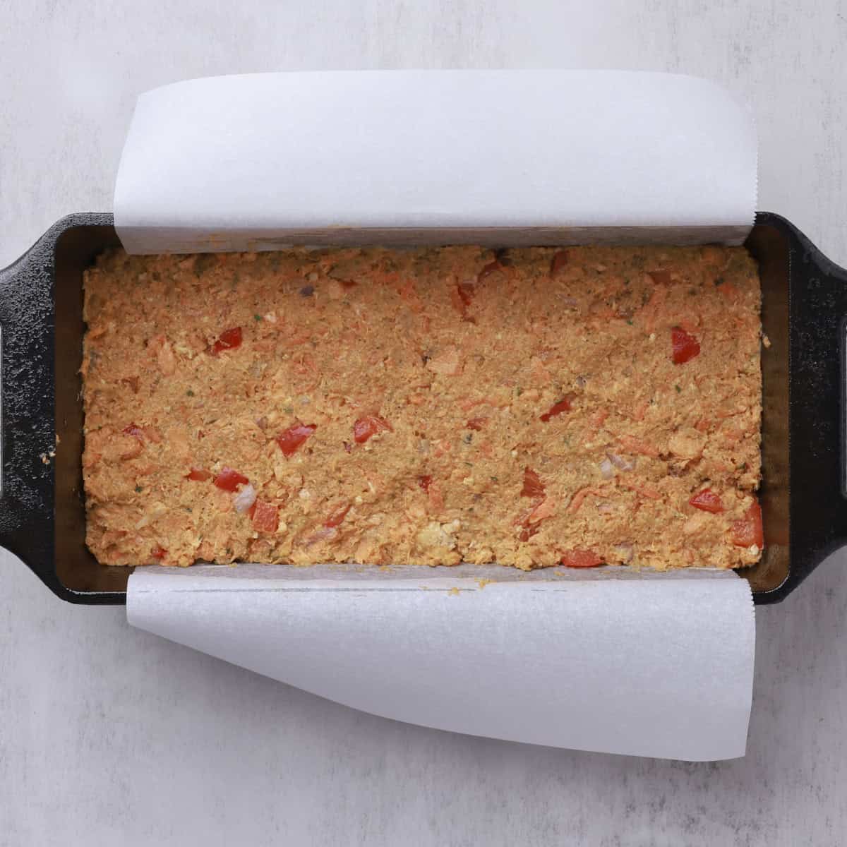 A loaf pan with the salmon loaf mixture pressed into it. 